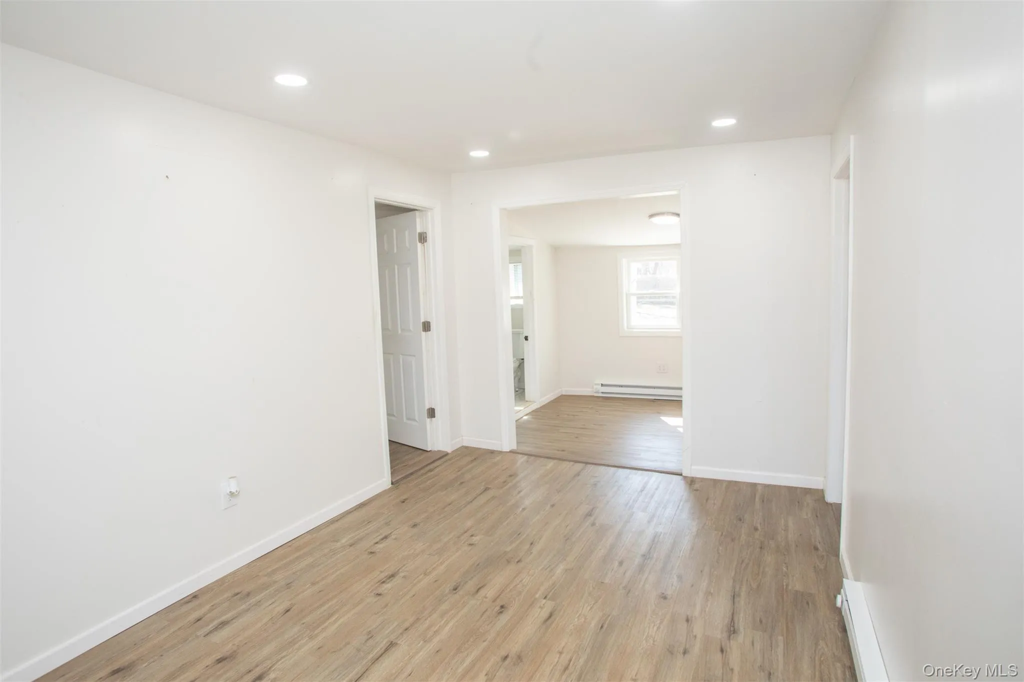 Unfurnished room featuring baseboards, recessed lighting, a baseboard heating unit, and light wood-style floors Unfurnished room featuring baseboards, recessed lighting, a baseboard heating unit, and light wood-style floors
