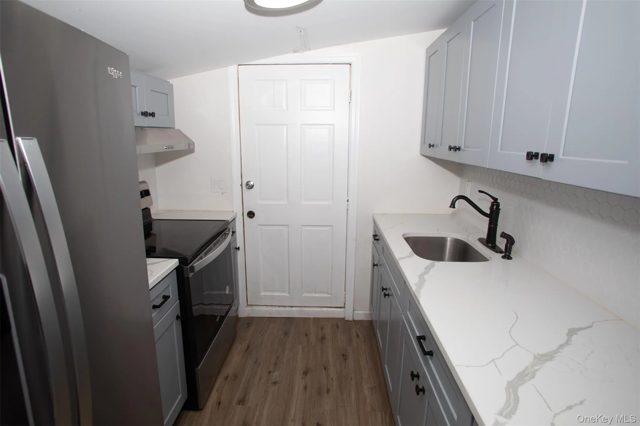 Kitchen with range hood, a sink, dark wood-style floors, range with electric stovetop, and freestanding refrigerator Kitchen with range hood, a sink, dark wood-style floors, range with electric stovetop, and freestanding refrigerator