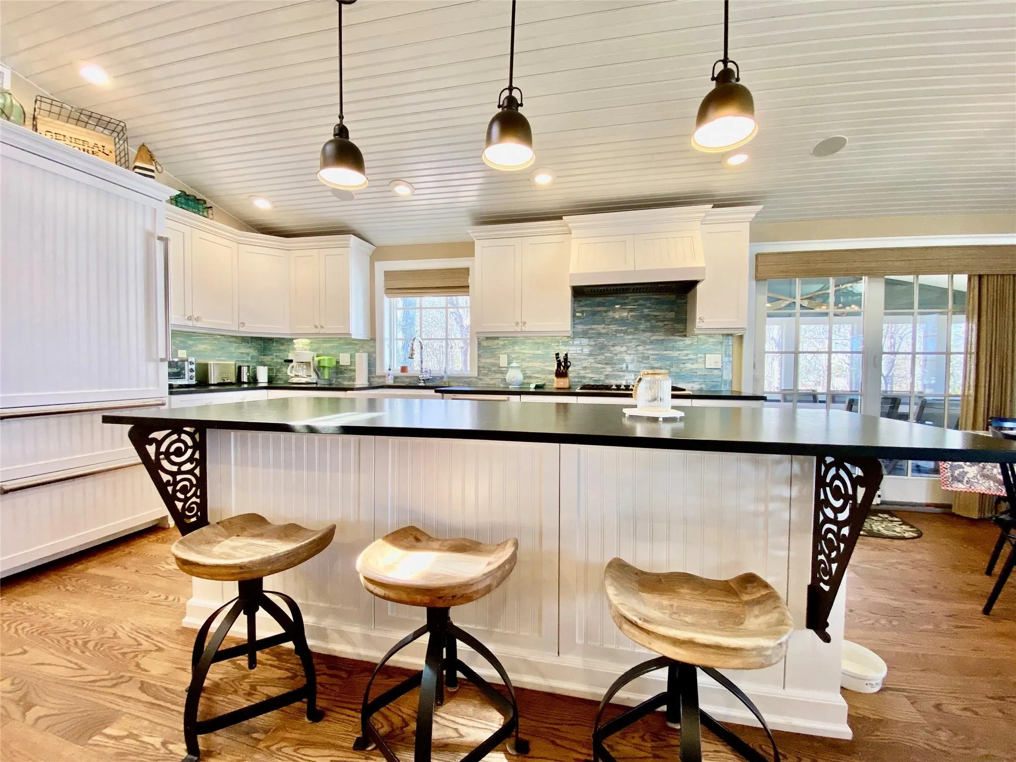 Kitchen featuring a breakfast bar, white cabinetry, stone countertops, and light wood-style floors Kitchen featuring a breakfast bar, white cabinetry, stone countertops, and light wood-style floors
