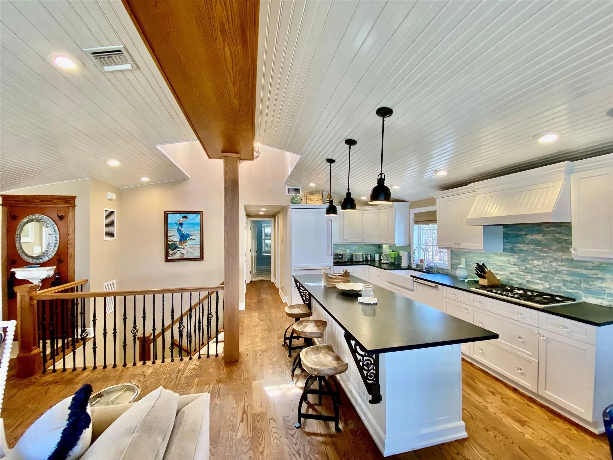 Kitchen with custom range hood, stone countertops, stainless steel gas stovetop, and lofted ceiling Kitchen with custom range hood, stone countertops, stainless steel gas stovetop, and lofted ceiling