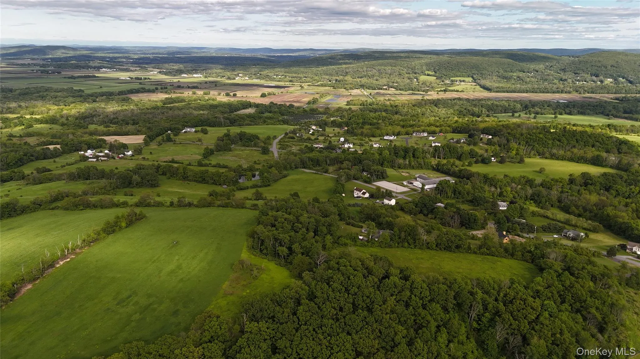 Aerial overview of property's location with a mountain backdrop and a forest Aerial overview of property's location with a mountain backdrop and a forest
