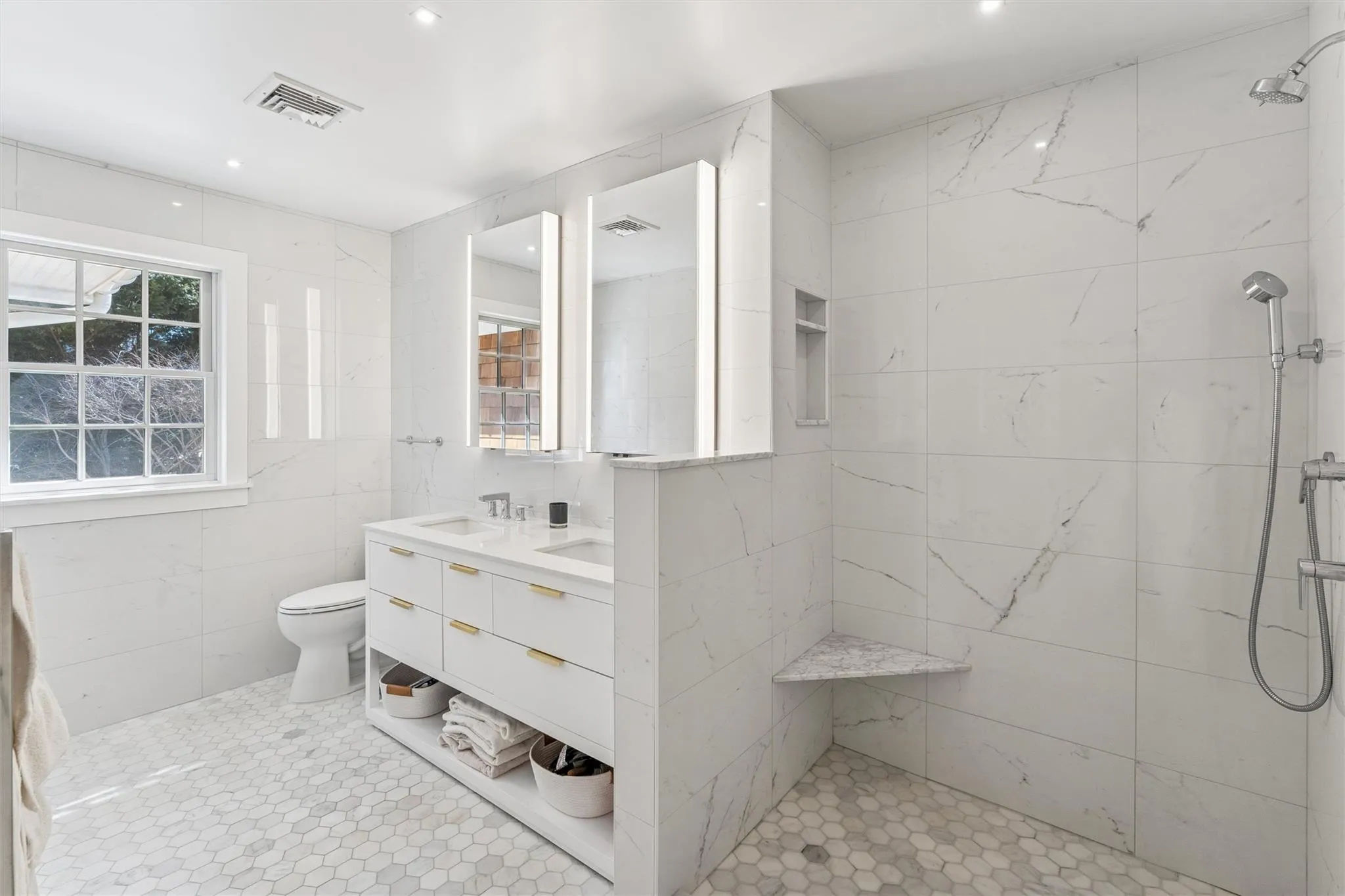 Bathroom with toilet, tiled shower, a sink, visible vents, and tile walls Bathroom with toilet, tiled shower, a sink, visible vents, and tile walls