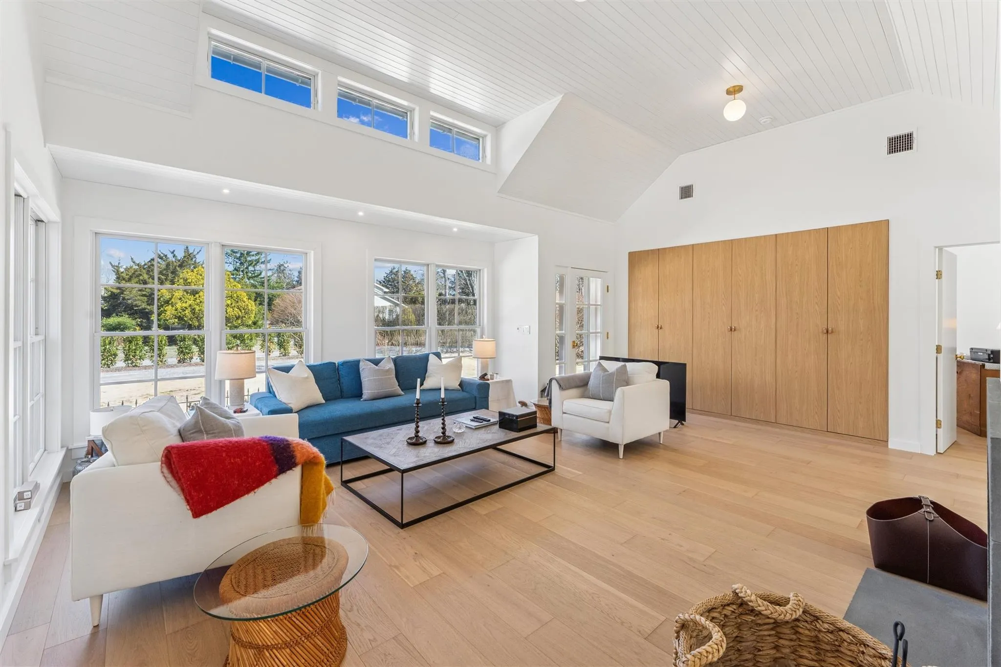 Living room with visible vents, high vaulted ceiling, light wood finished floors, and a wealth of natural light Living room with visible vents, high vaulted ceiling, light wood finished floors, and a wealth of natural light