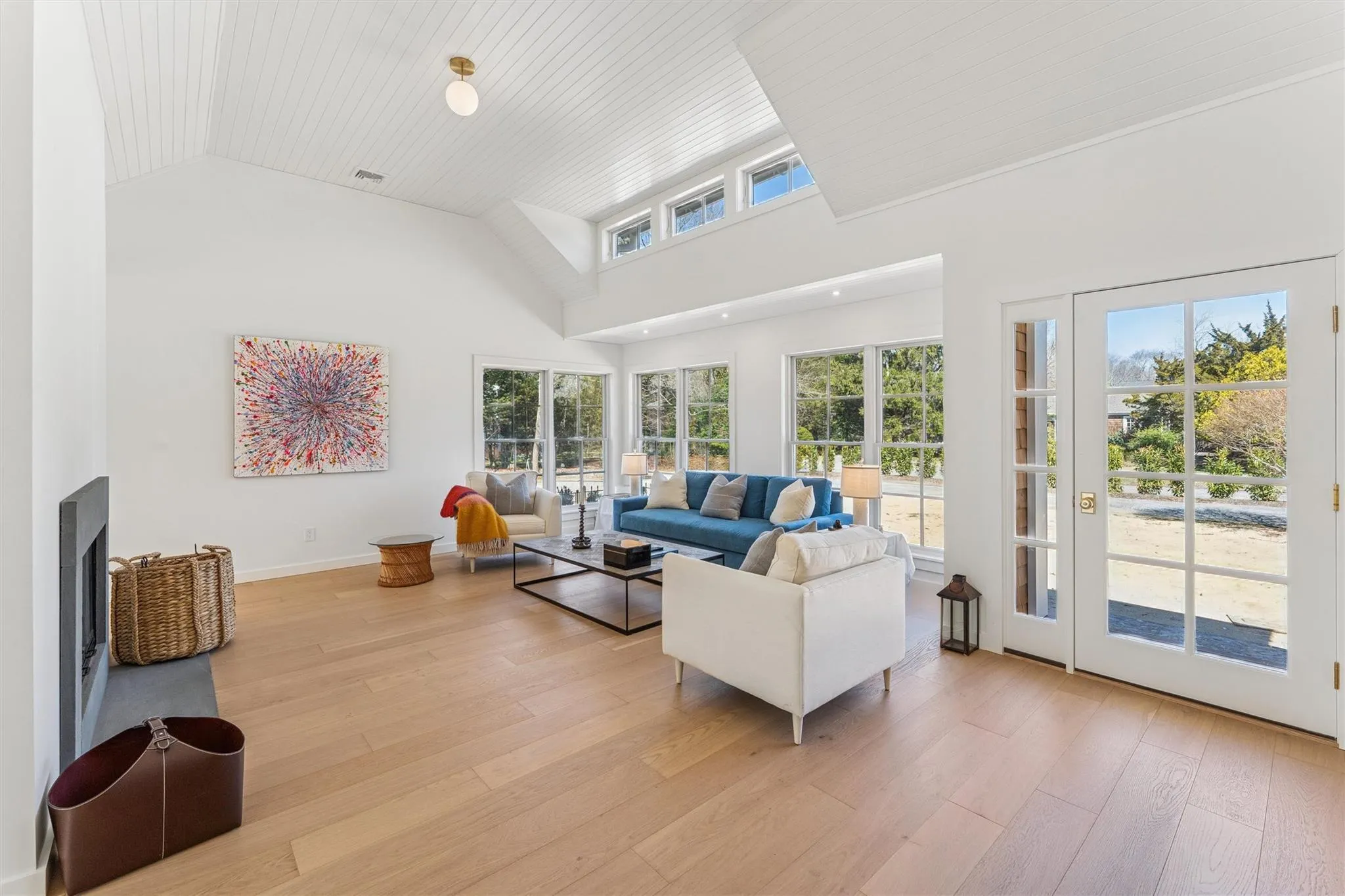 Living room featuring light wood-style flooring, high vaulted ceiling, baseboards, and visible vents Living room featuring light wood-style flooring, high vaulted ceiling, baseboards, and visible vents