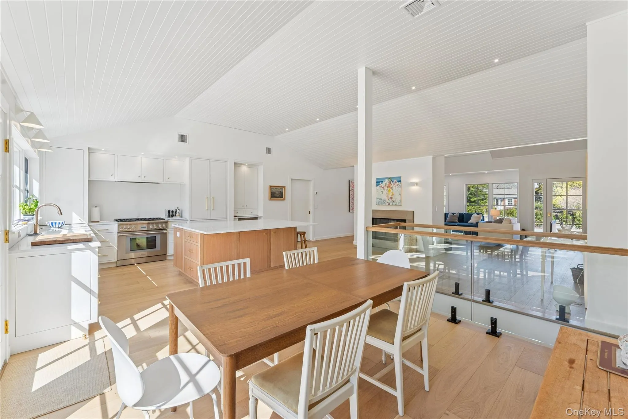 Dining area featuring a fireplace, light wood-style floors, lofted ceiling, and visible vents Dining area featuring a fireplace, light wood-style floors, lofted ceiling, and visible vents