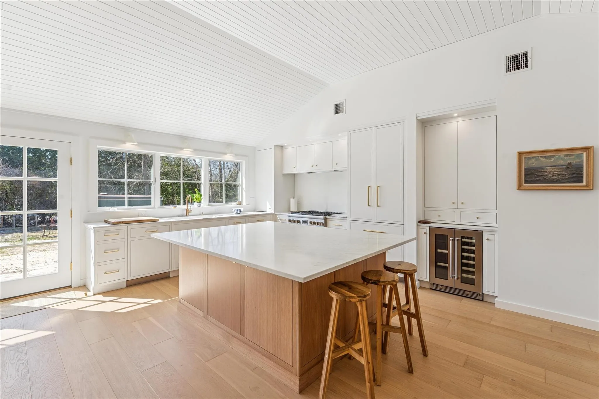 Kitchen with a center island, beverage cooler, lofted ceiling, light wood-type flooring, and visible vents Kitchen with a center island, beverage cooler, lofted ceiling, light wood-type flooring, and visible vents