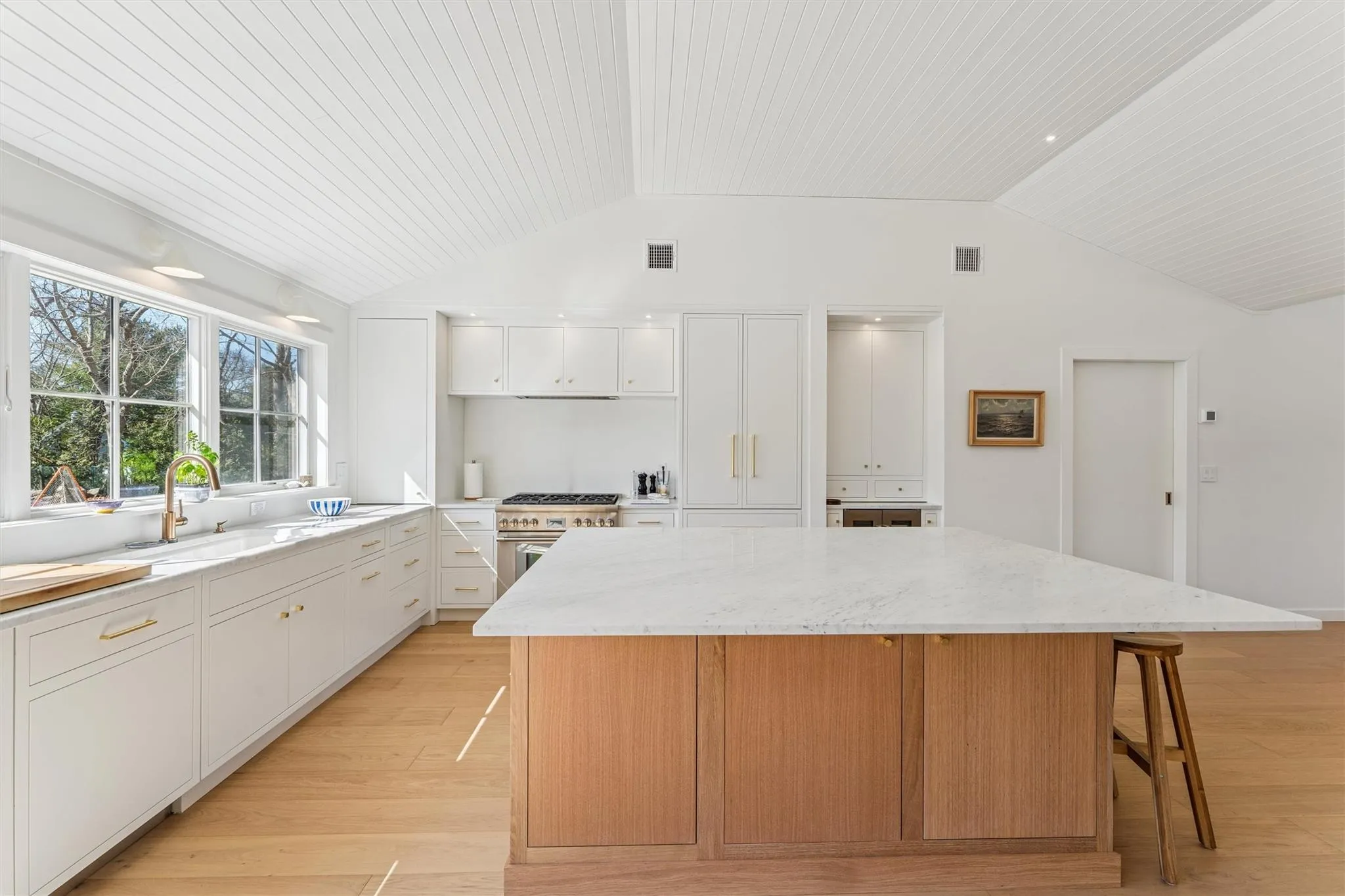 Kitchen with vaulted ceiling, a center island, high end stainless steel range, a sink, and visible vents Kitchen with vaulted ceiling, a center island, high end stainless steel range, a sink, and visible vents