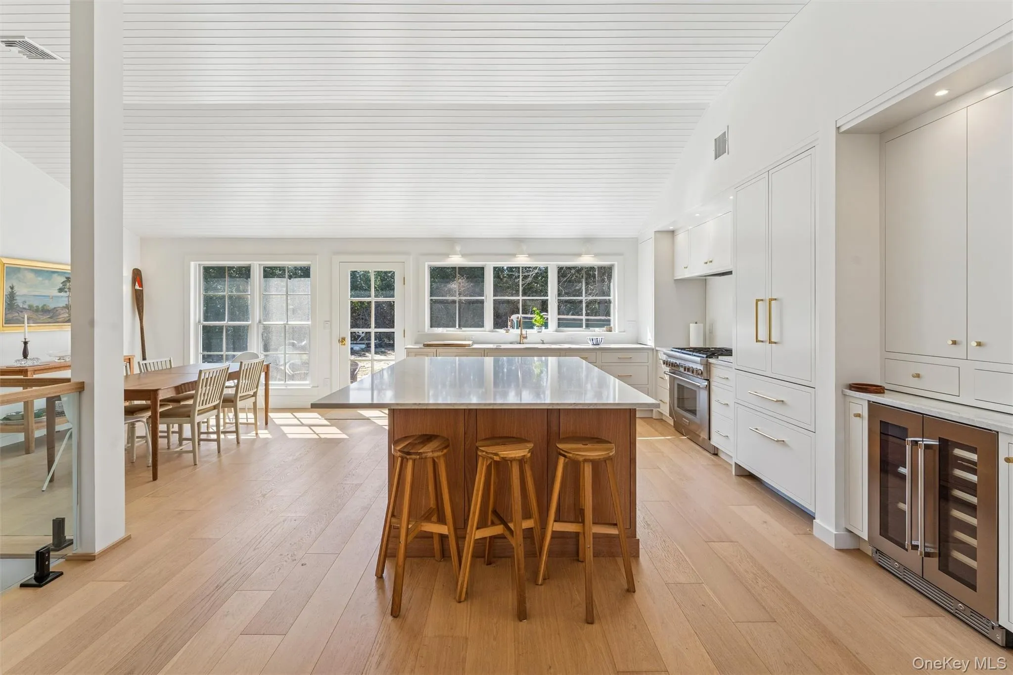 Kitchen featuring a kitchen bar, wine cooler, stainless steel range, vaulted ceiling, and a center island Kitchen featuring a kitchen bar, wine cooler, stainless steel range, vaulted ceiling, and a center island