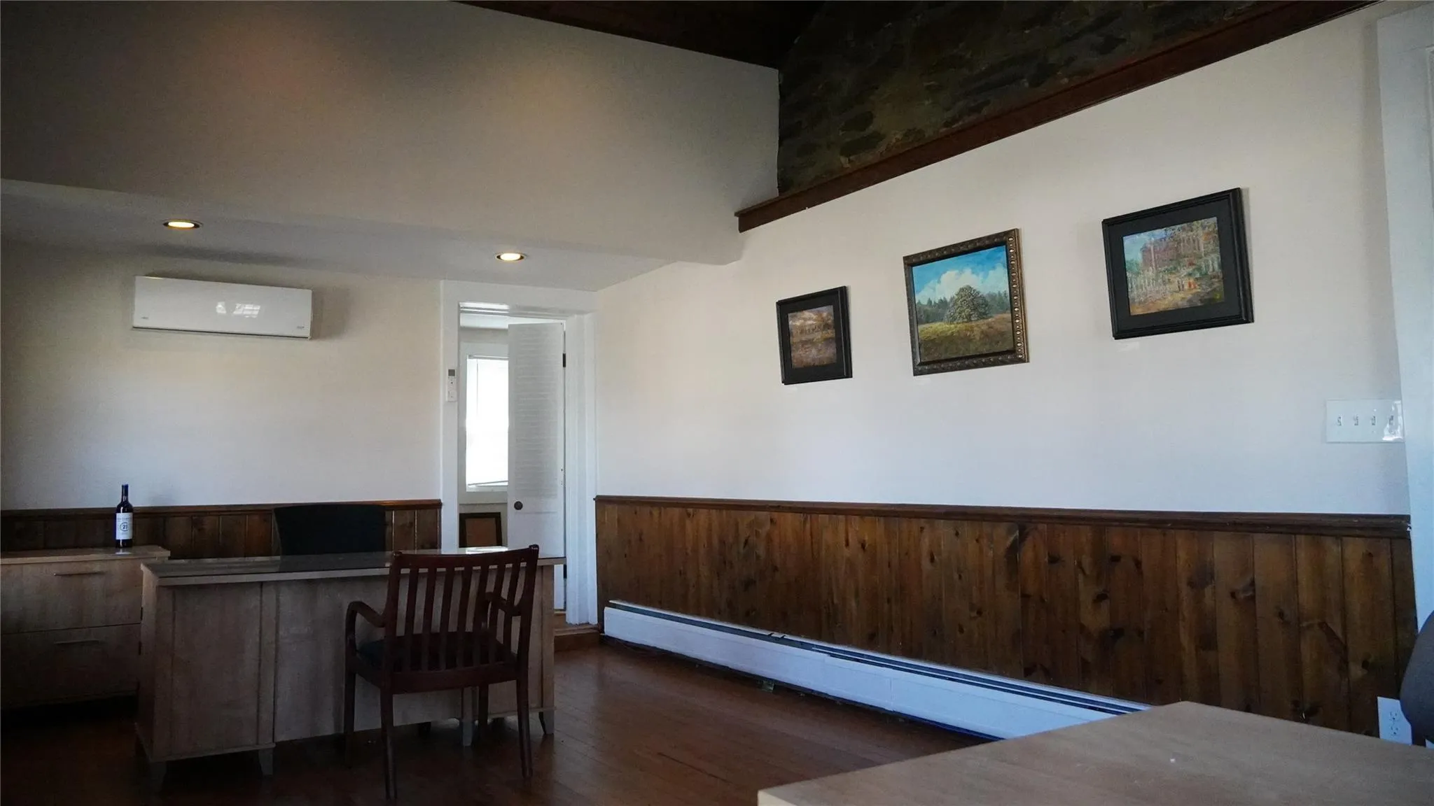 Home office featuring a wainscoted wall, wood walls, wood finished floors, a baseboard heating unit, and a wall unit AC Home office featuring a wainscoted wall, wood walls, wood finished floors, a baseboard heating unit, and a wall unit AC