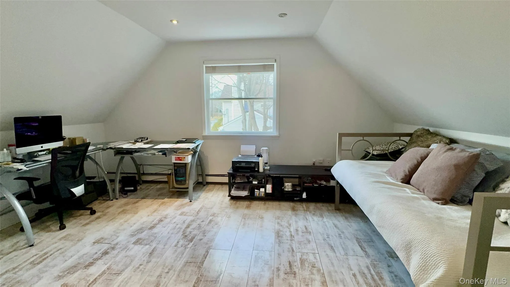 Bedroom with baseboard heating, vaulted ceiling, and wood finished floors