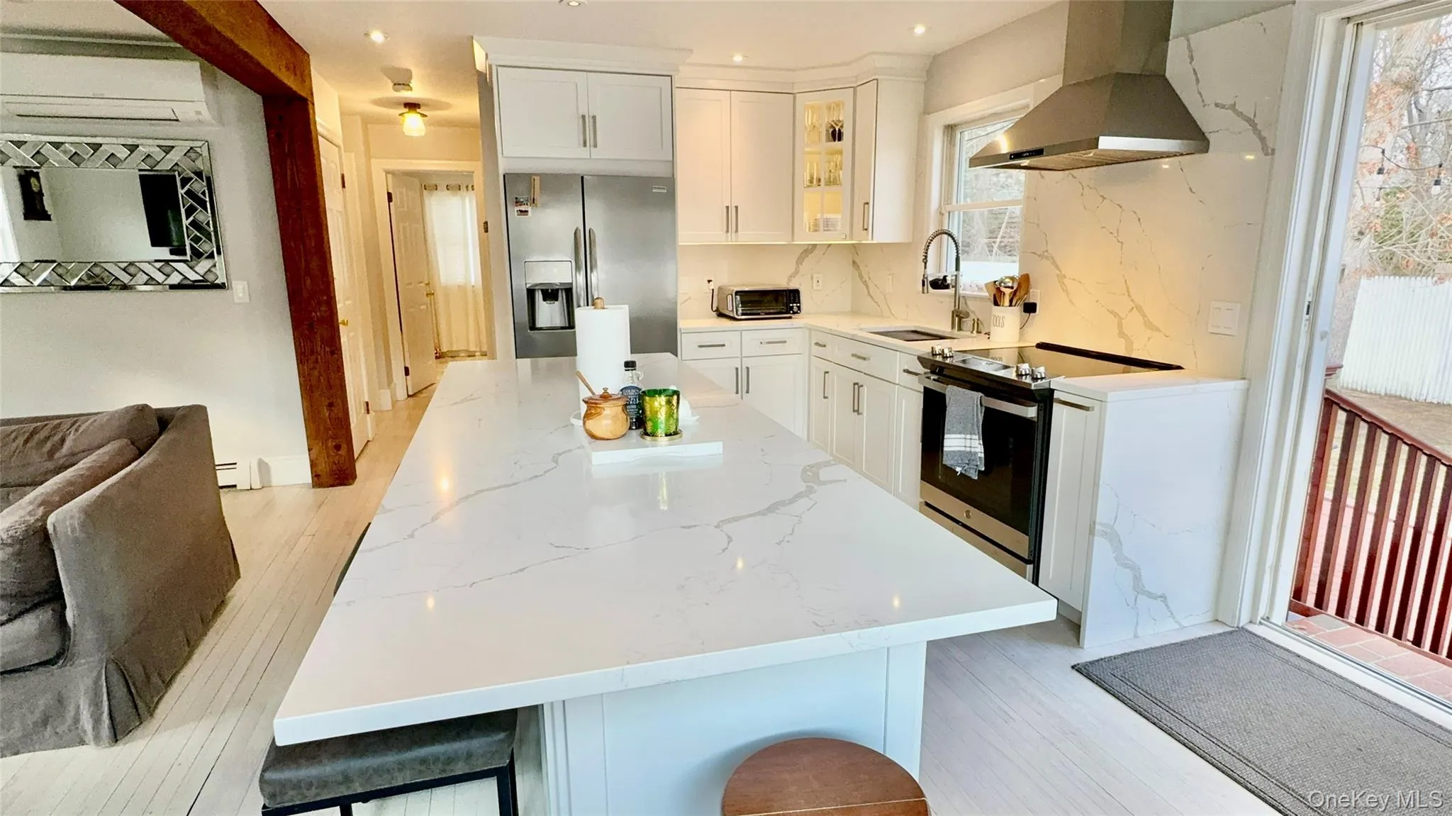 Kitchen featuring a center island, appliances with stainless steel finishes, a sink, ventilation hood, and backsplash