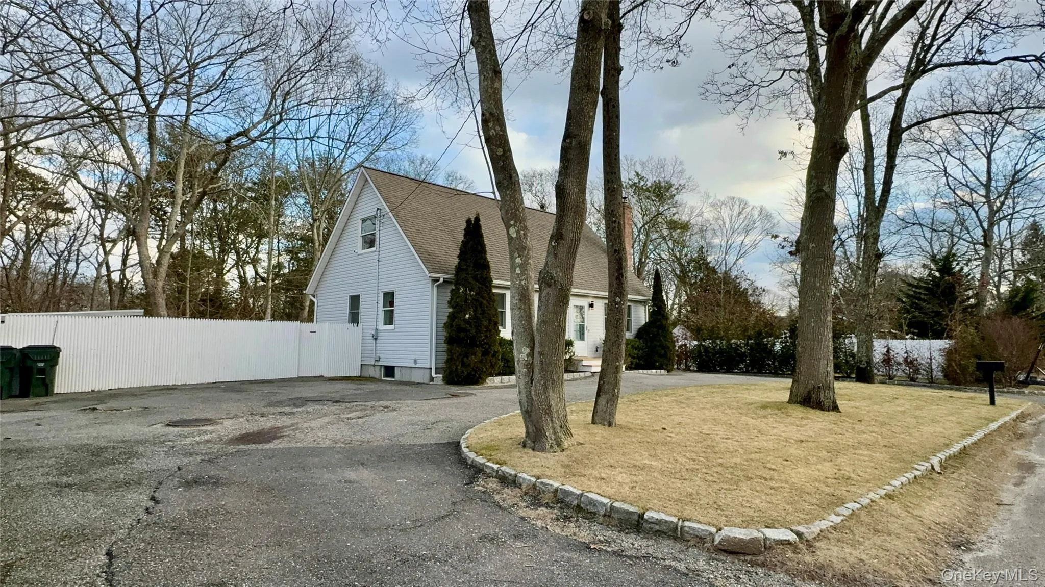 View of home's exterior featuring driveway, a shingled roof, and fence