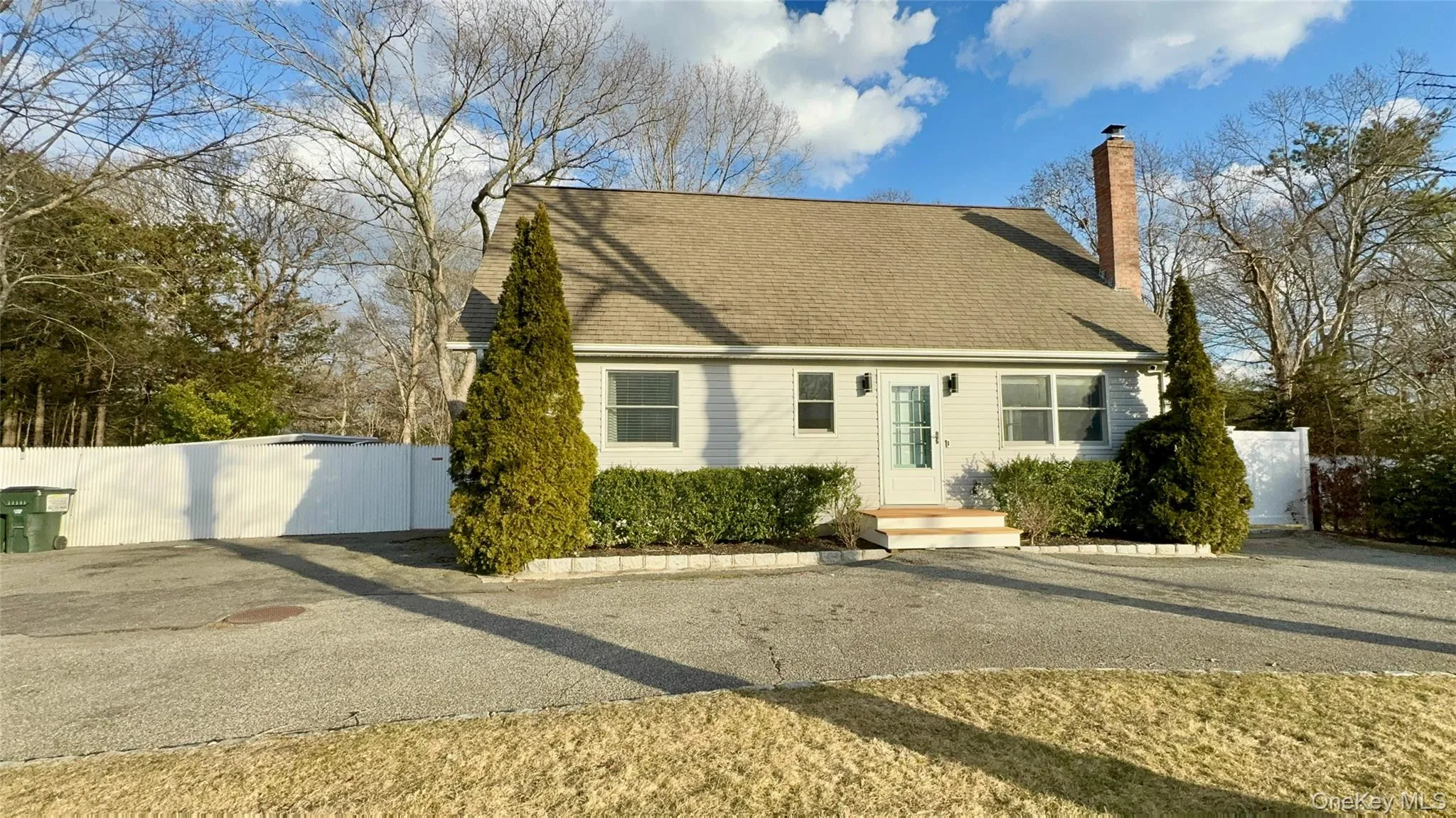 New england style home featuring a chimney, fence, and a gate
