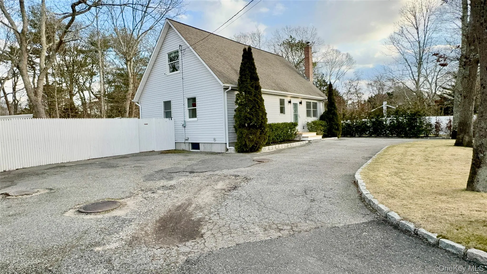View of side of home with roof with shingles, a chimney, fence, aphalt driveway, and entry steps