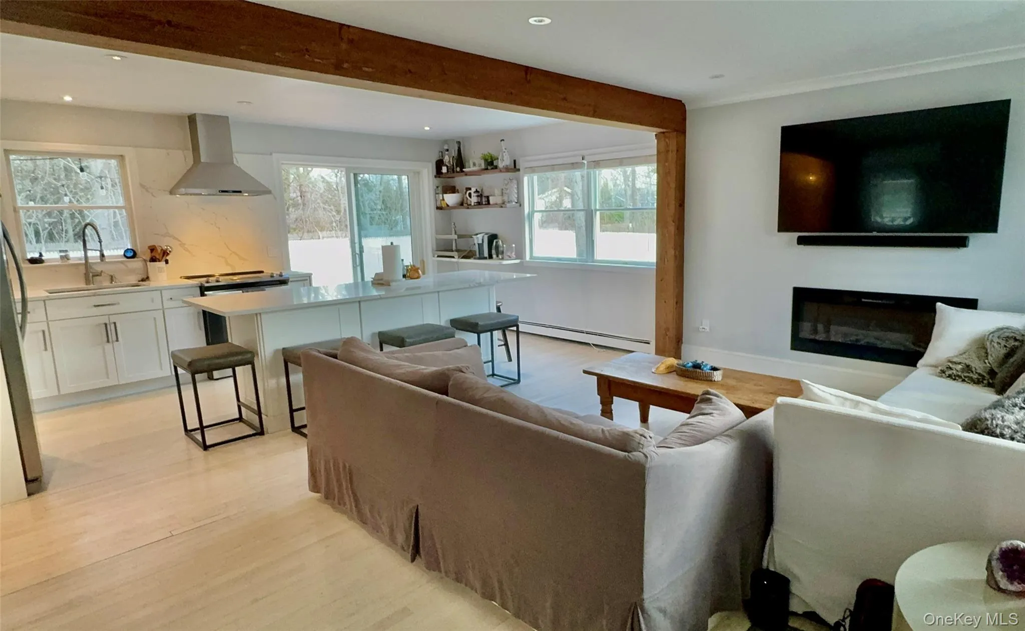 Living room featuring baseboard heating, recessed lighting, beam ceiling, and light wood-type flooring