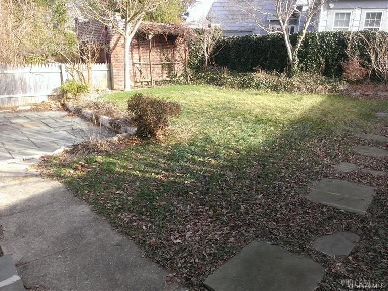 Fully-fenced back yard with plantings and grapevine arbor Fully-fenced back yard with plantings and grapevine arbor