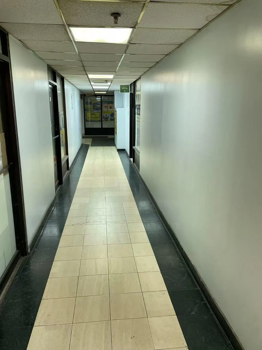 Corridor with baseboards, a drop ceiling, and dark tile patterned floors Corridor with baseboards, a drop ceiling, and dark tile patterned floors