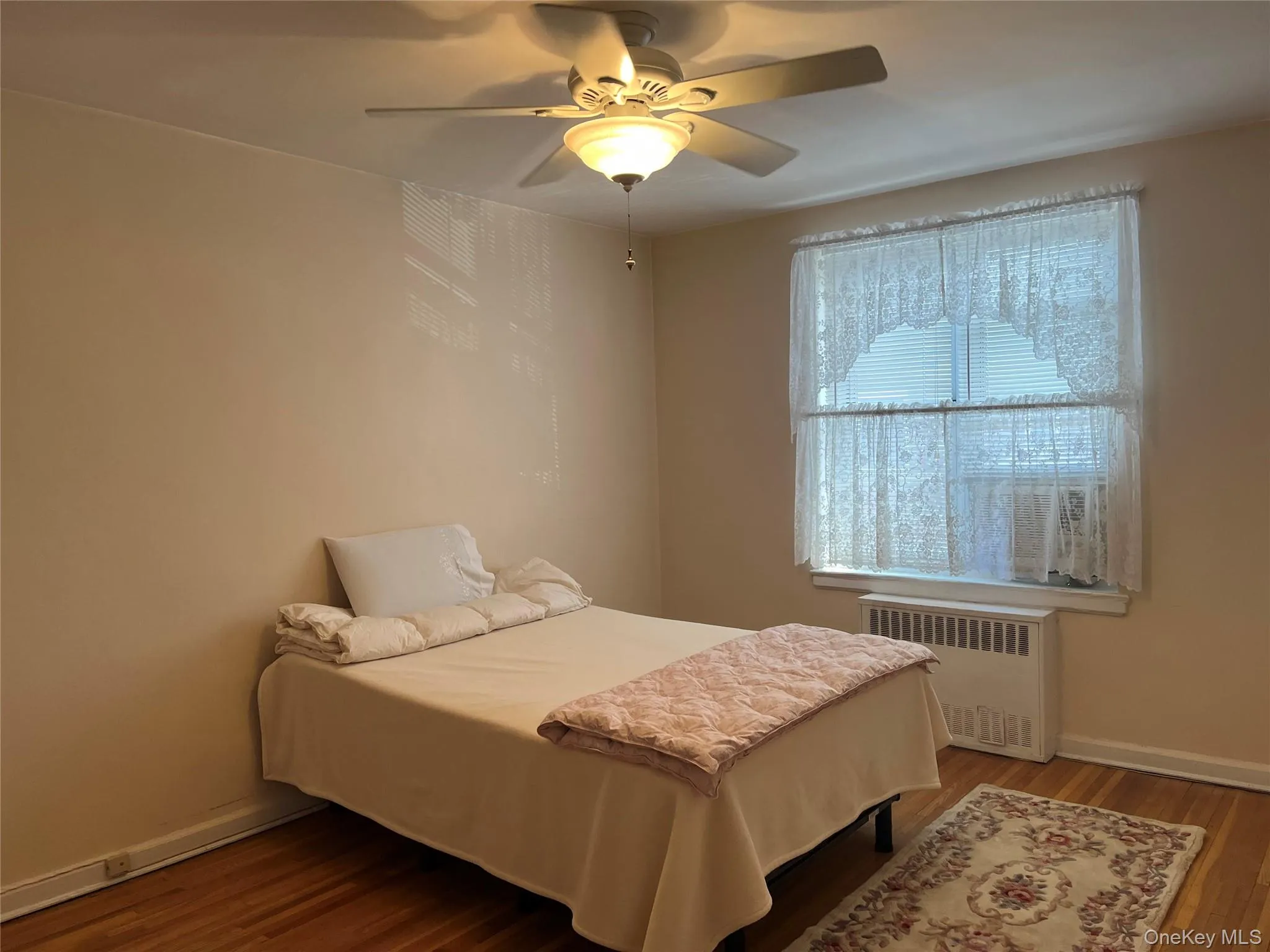 2nd Bedroom with baseboards, ceiling fan, wood finished floors, and radiator heating unit 2nd Bedroom with baseboards, ceiling fan, wood finished floors, and radiator heating unit