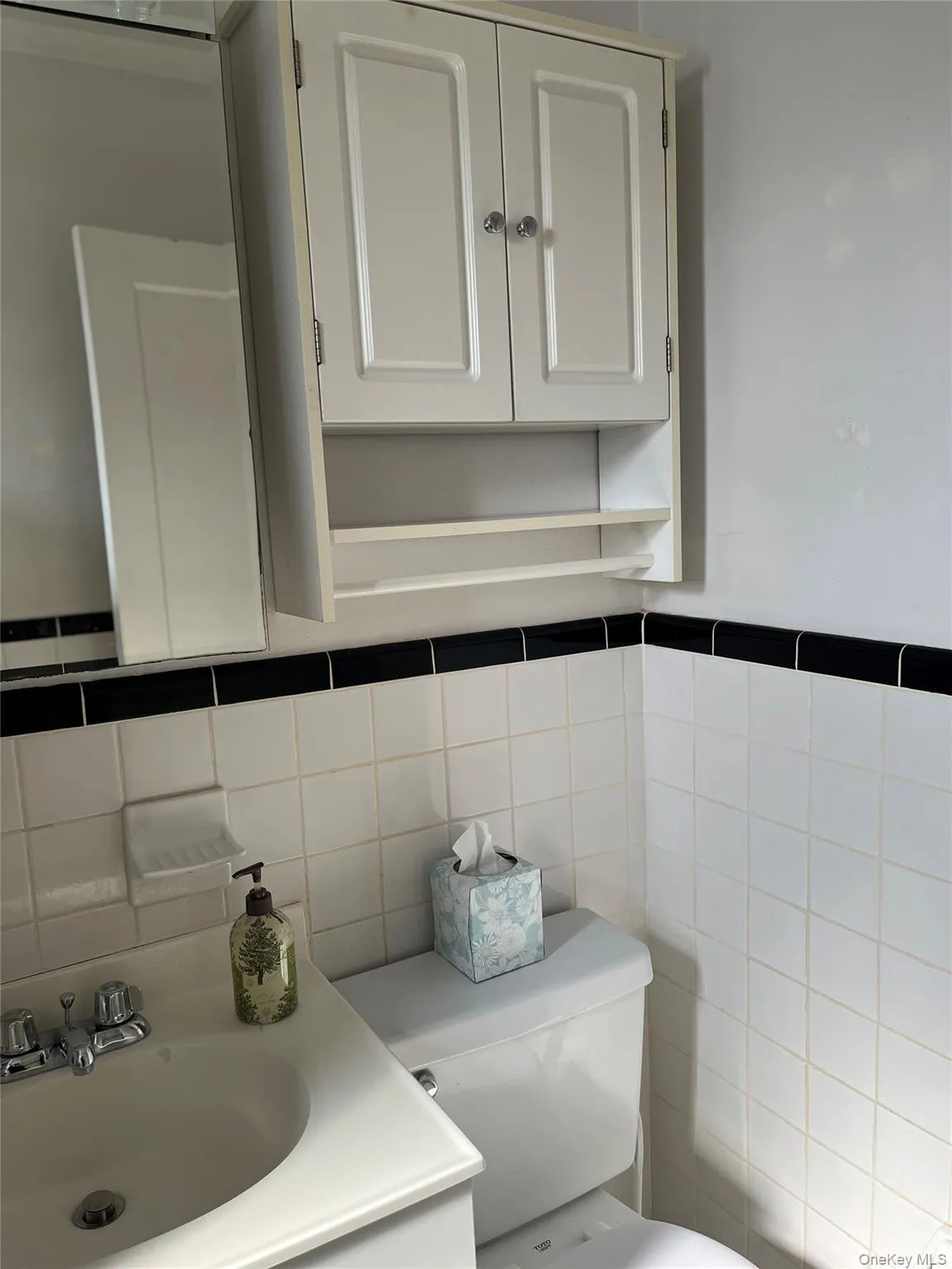 Half bathroom with tile walls, toilet, and a sink Half bathroom with tile walls, toilet, and a sink