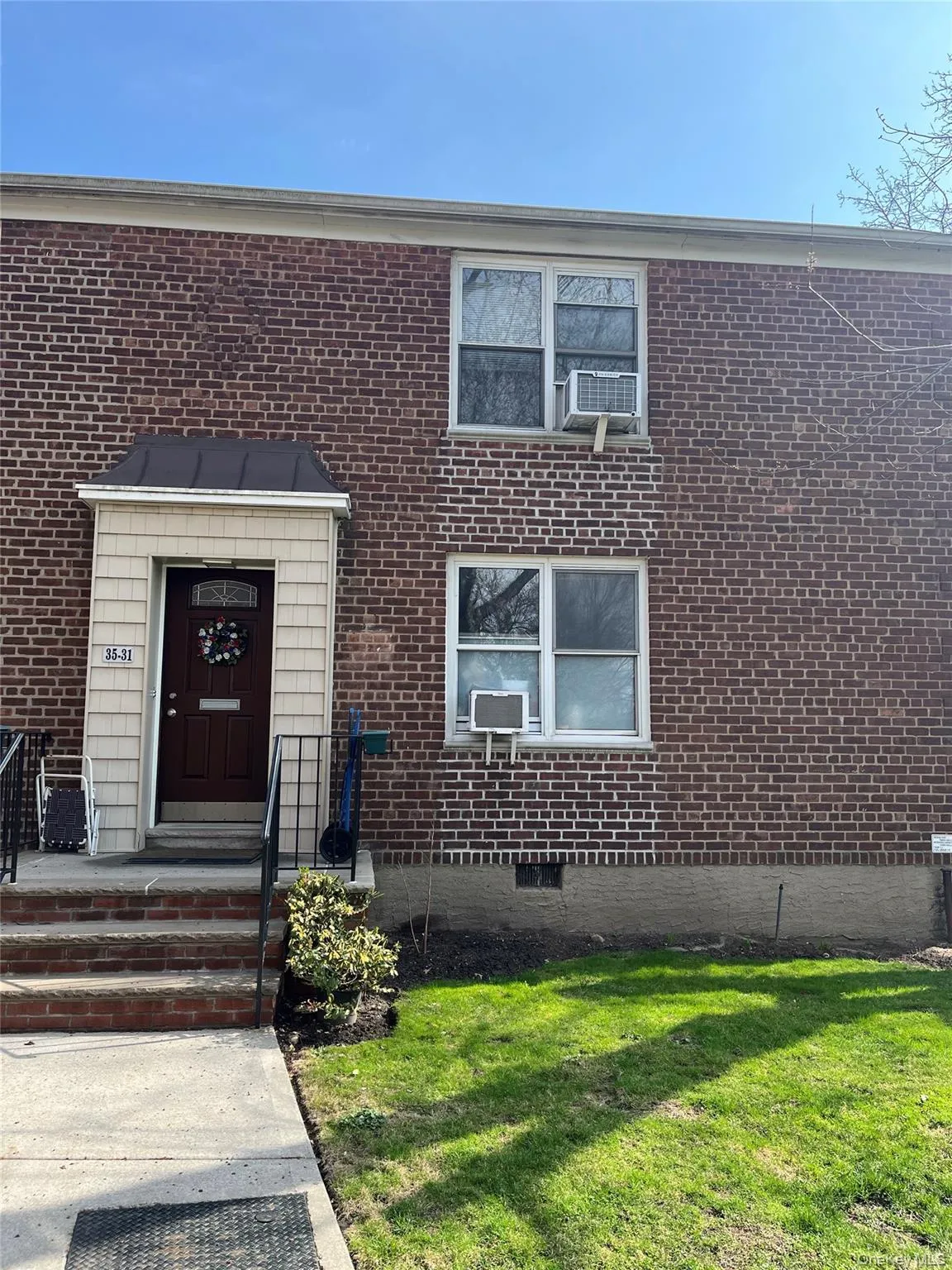 Doorway to property featuring brick siding, cooling unit, and a yard Doorway to property featuring brick siding, cooling unit, and a yard