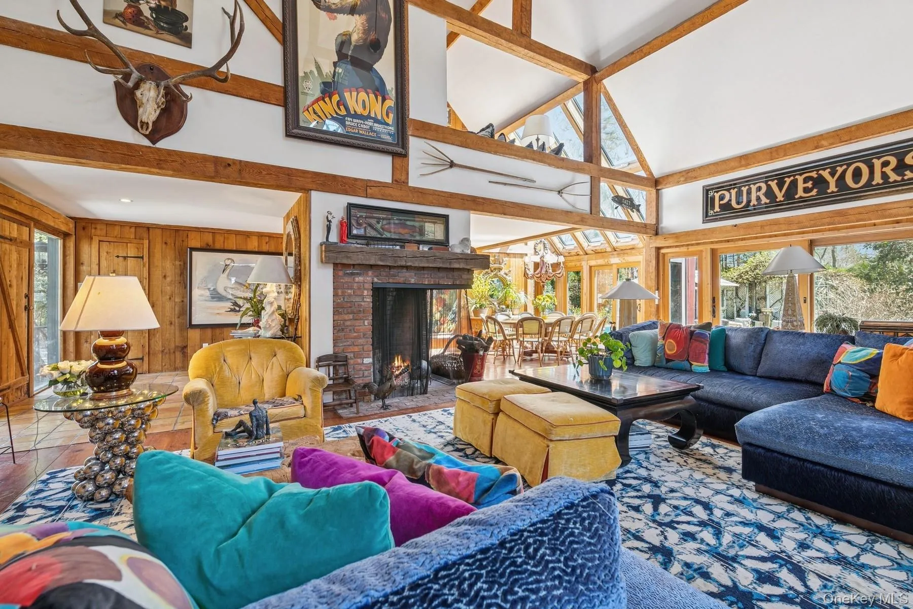 Living area with beamed ceiling, wooden walls, high vaulted ceiling, and a fireplace Living area with beamed ceiling, wooden walls, high vaulted ceiling, and a fireplace