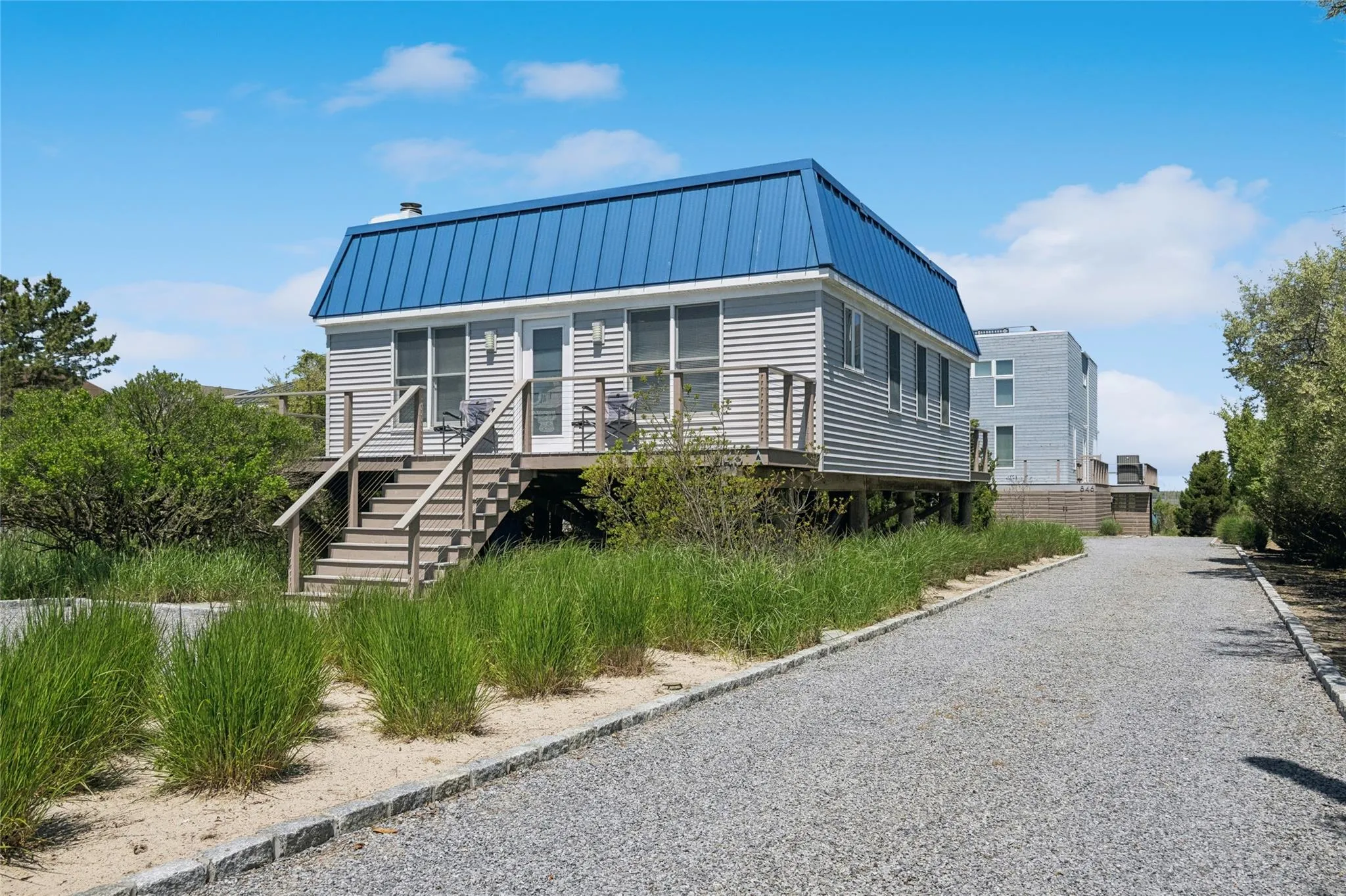 View of front of house featuring a standing seam roof, driveway, stairway, and metal roof View of front of house featuring a standing seam roof, driveway, stairway, and metal roof