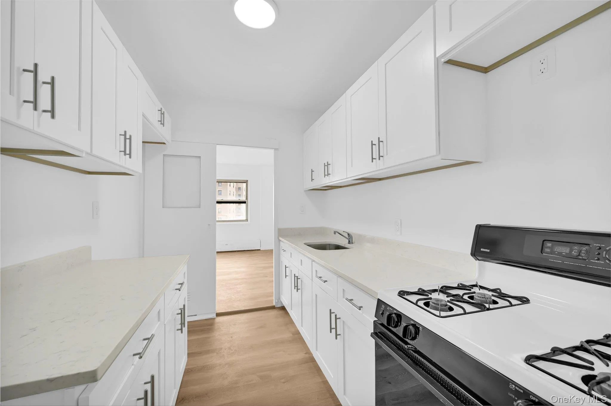 Kitchen featuring a sink, white cabinets, gas range, and light wood-style floors Kitchen featuring a sink, white cabinets, gas range, and light wood-style floors