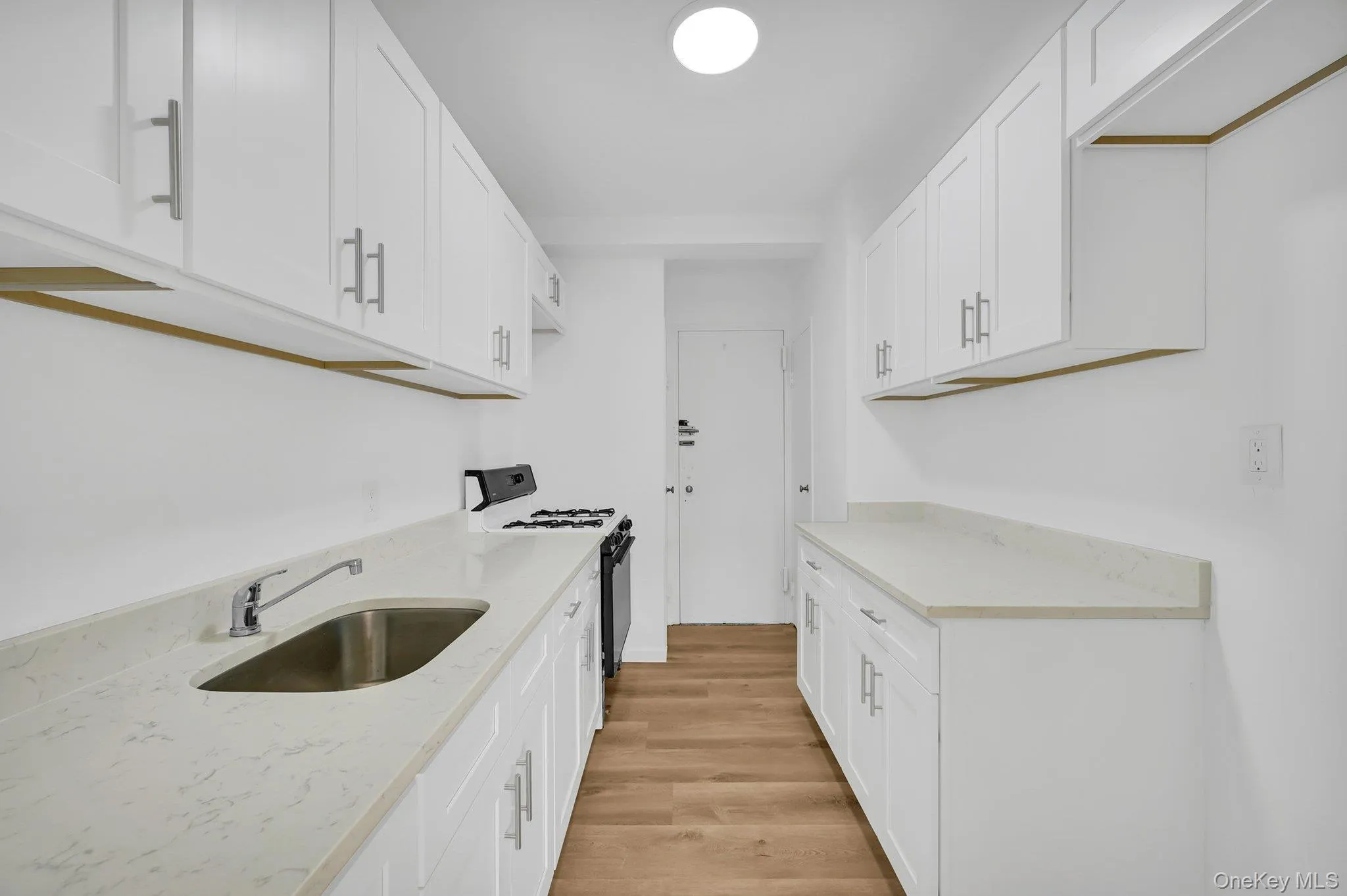 Kitchen featuring light wood finished floors, white cabinetry, black range with gas cooktop, and a sink Kitchen featuring light wood finished floors, white cabinetry, black range with gas cooktop, and a sink