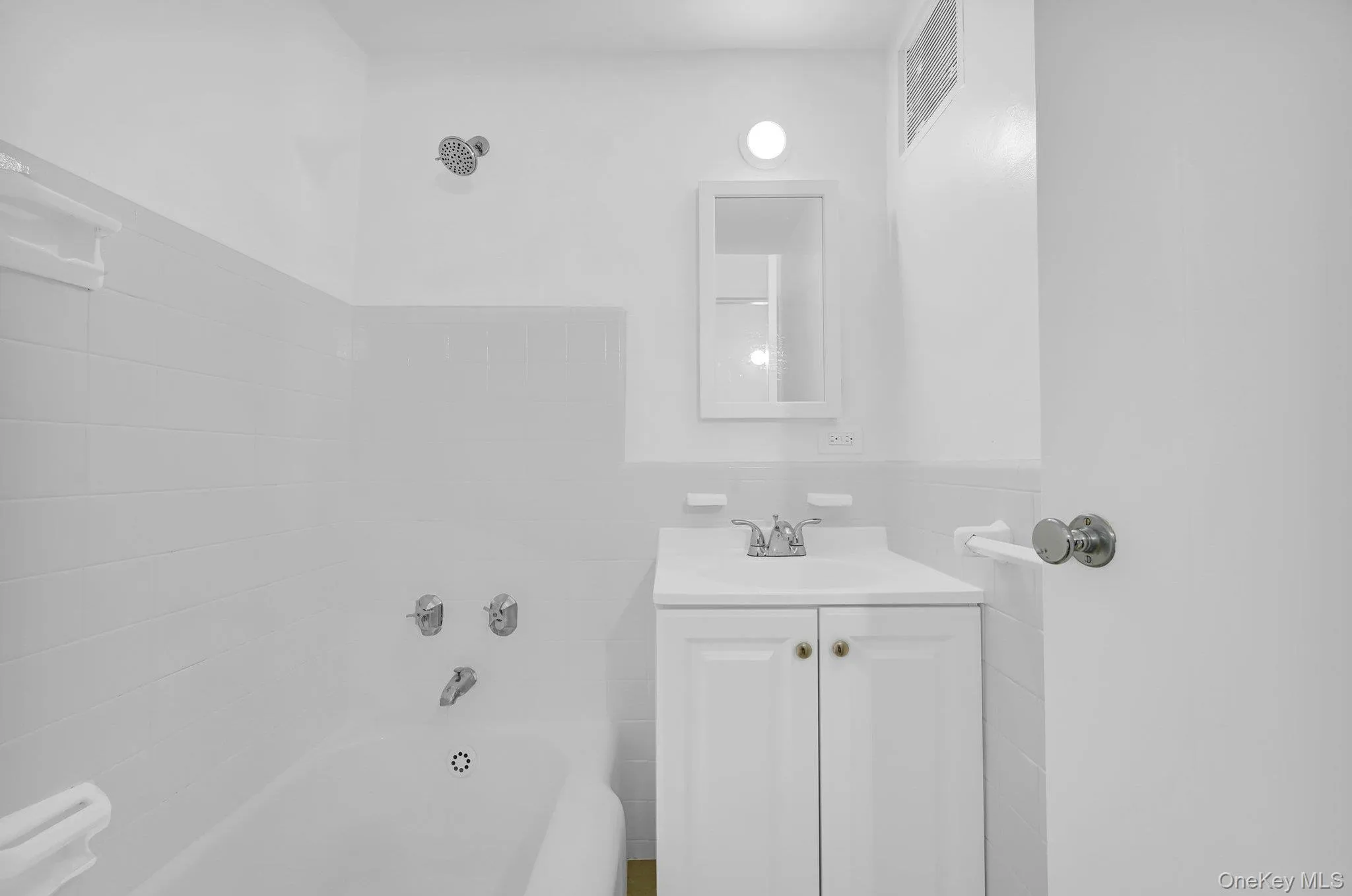 Full bathroom featuring visible vents, a tub to relax in, and vanity Full bathroom featuring visible vents, a tub to relax in, and vanity