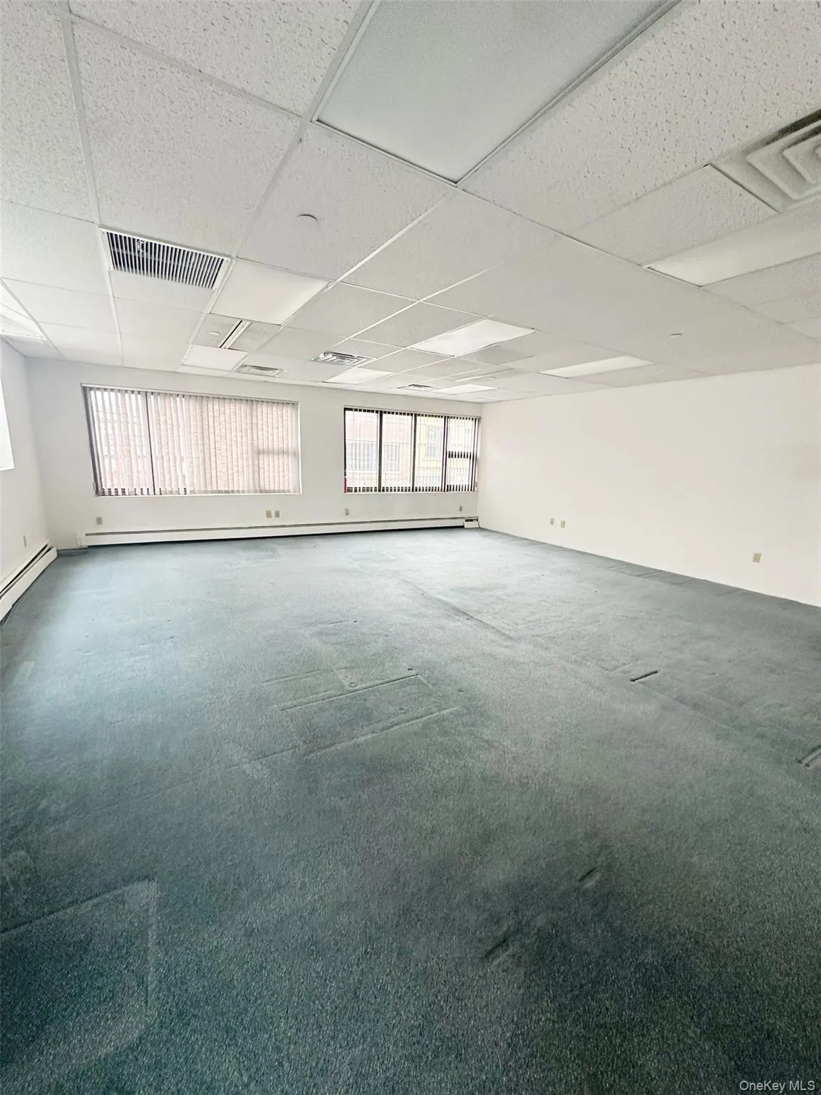 Carpeted spare room featuring visible vents and a paneled ceiling Carpeted spare room featuring visible vents and a paneled ceiling