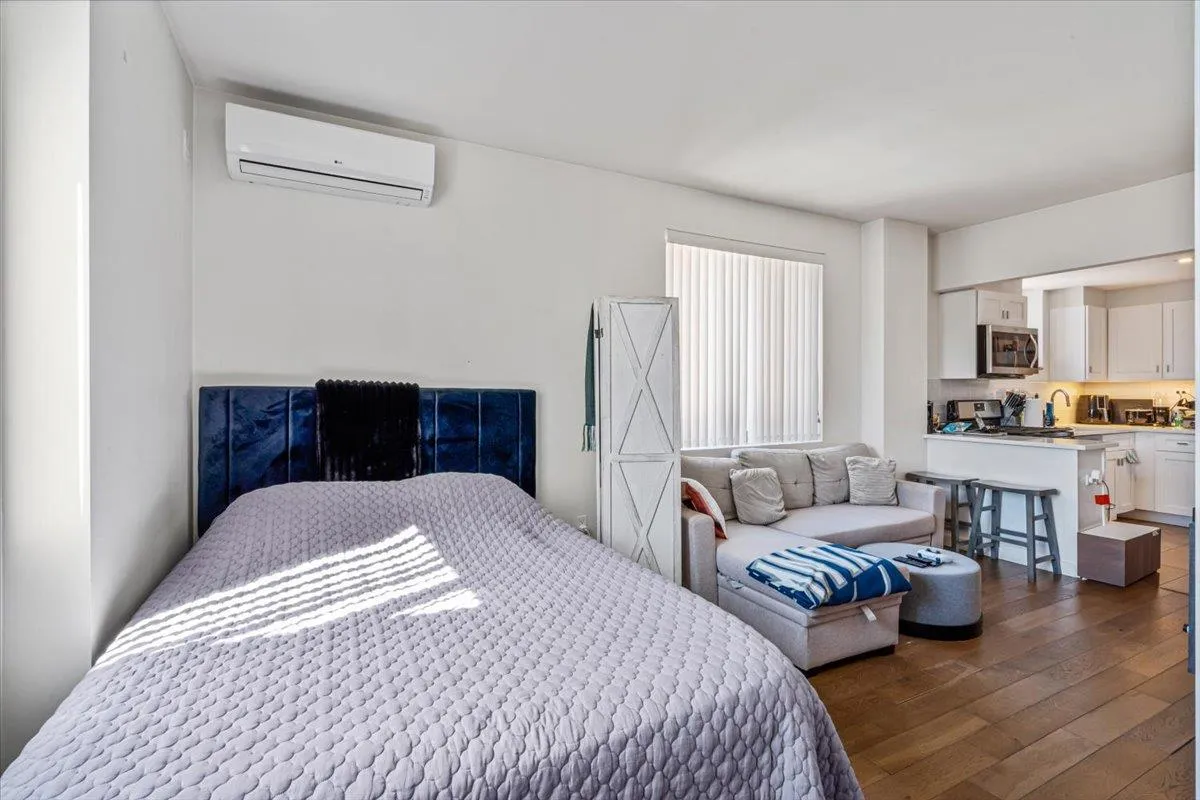 Bedroom featuring dark wood-type flooring and an AC wall unit Bedroom featuring dark wood-type flooring and an AC wall unit