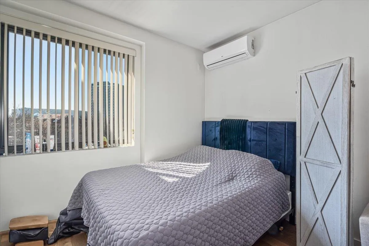 Bedroom with a wall unit AC and wood finished floors Bedroom with a wall unit AC and wood finished floors
