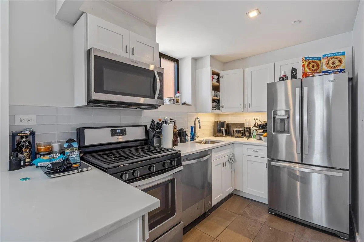 Kitchen with tasteful backsplash, light countertops, white cabinetry, stainless steel appliances, and a sink Kitchen with tasteful backsplash, light countertops, white cabinetry, stainless steel appliances, and a sink