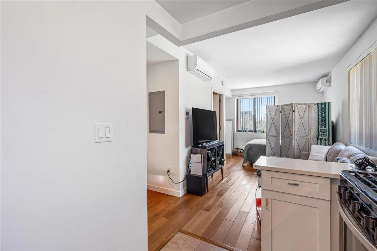 Kitchen featuring electric panel, a wall mounted AC, open floor plan, and light wood-style flooring Kitchen featuring electric panel, a wall mounted AC, open floor plan, and light wood-style flooring