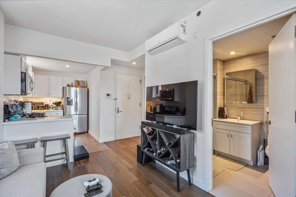 Living area with recessed lighting, light wood-style floors, an AC wall unit, and baseboards Living area with recessed lighting, light wood-style floors, an AC wall unit, and baseboards