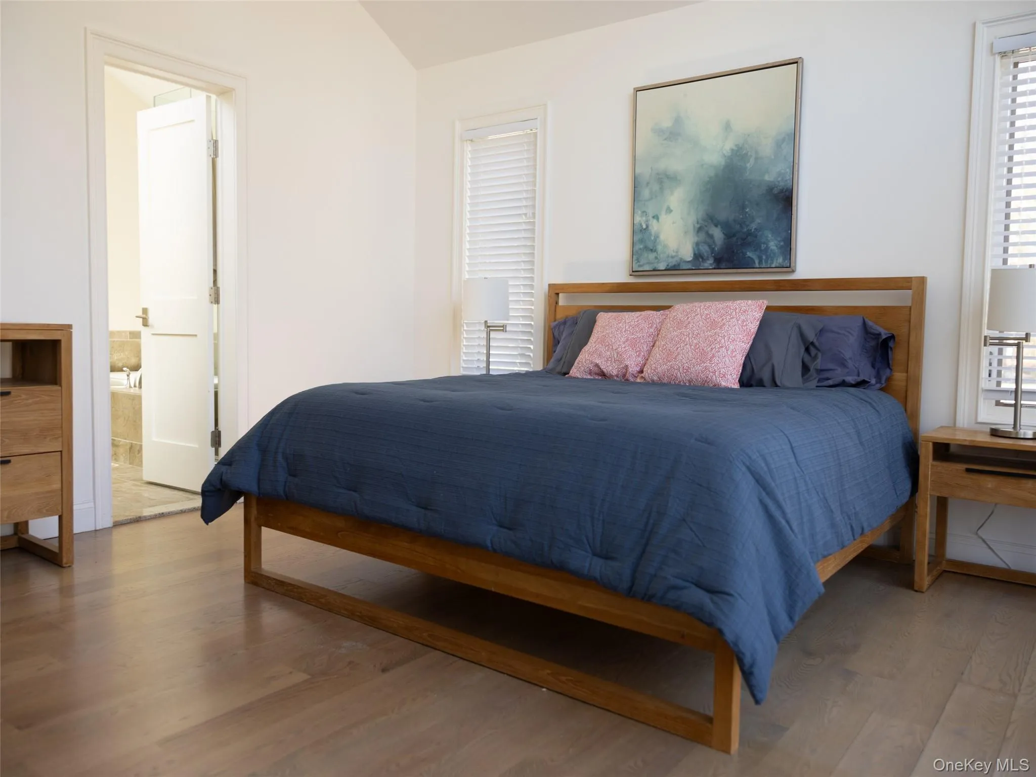 Bedroom with wood finished floors, ensuite bathroom, and lofted ceiling Bedroom with wood finished floors, ensuite bathroom, and lofted ceiling