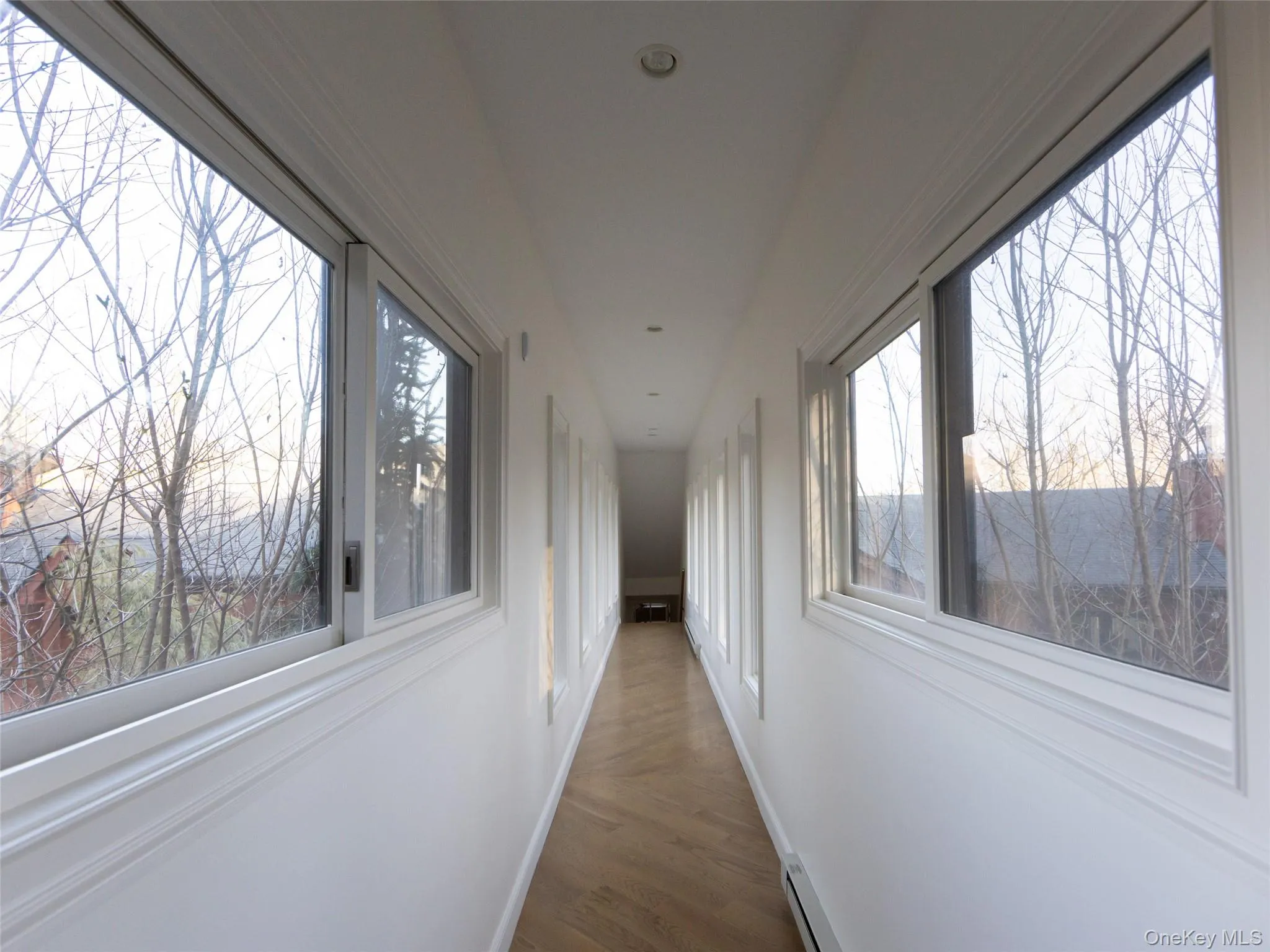 Corridor with wood finished floors, baseboards, and visible vents Corridor with wood finished floors, baseboards, and visible vents