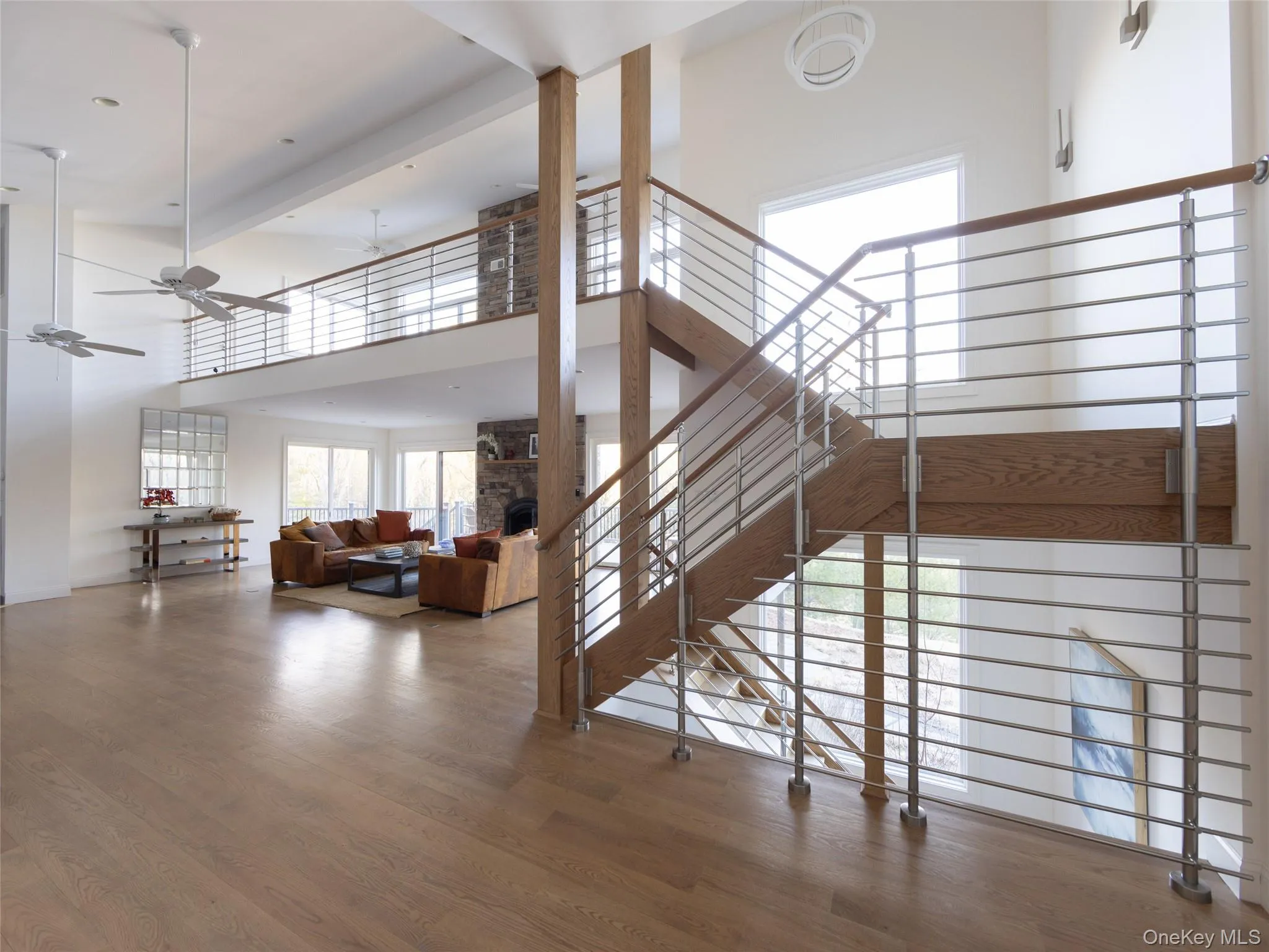 Stairway with a stone fireplace, a ceiling fan, a high ceiling, and wood finished floors Stairway with a stone fireplace, a ceiling fan, a high ceiling, and wood finished floors