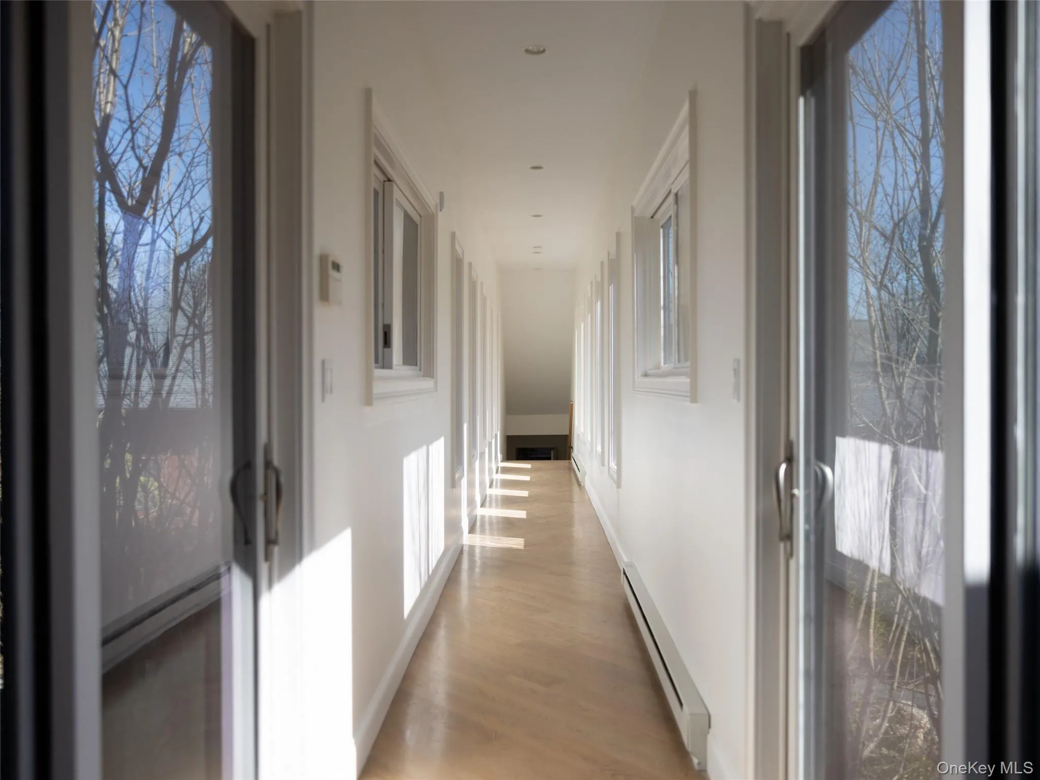 Corridor with light wood-type flooring and a baseboard radiator Corridor with light wood-type flooring and a baseboard radiator
