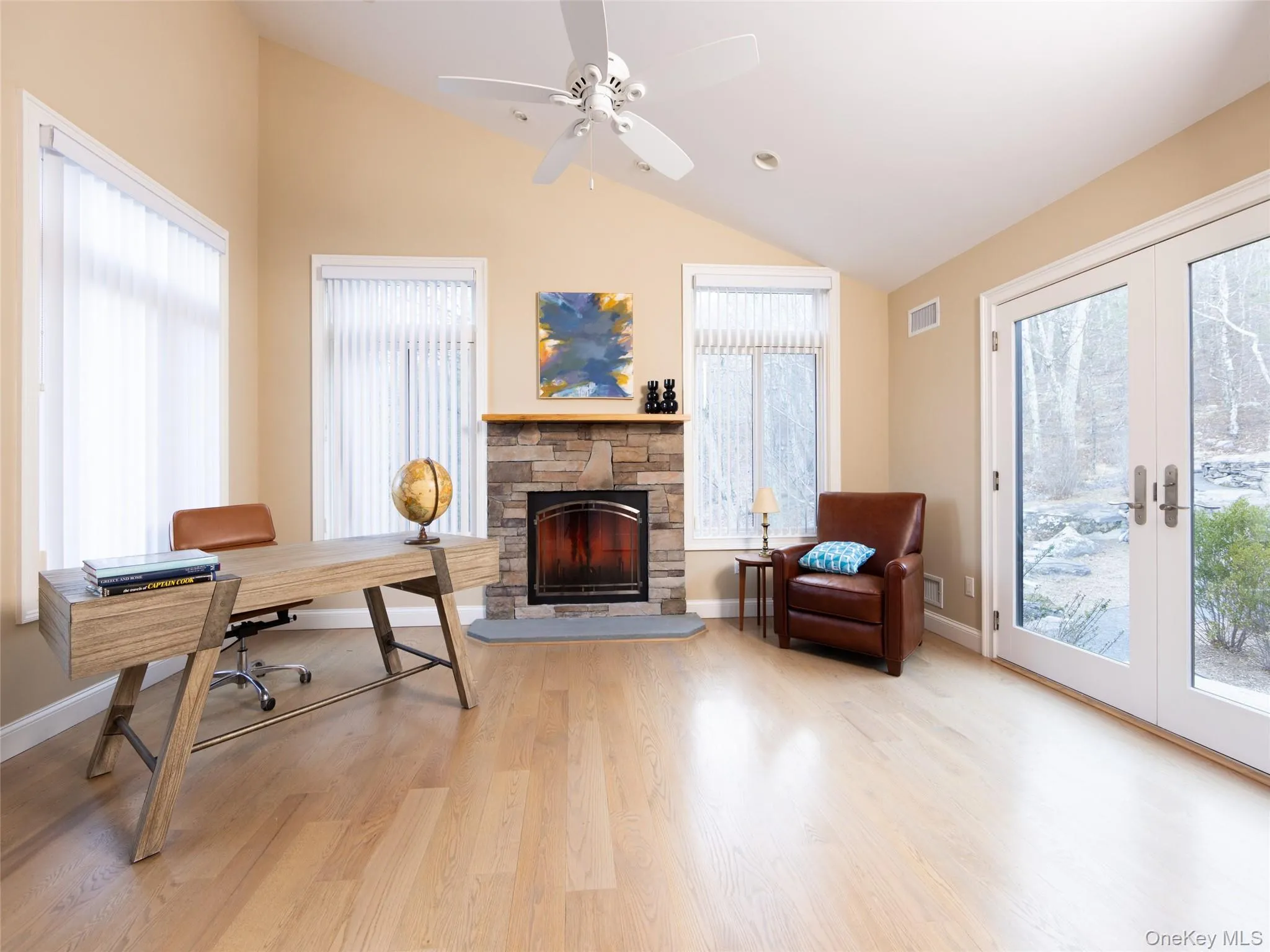 Office featuring french doors, a stone fireplace, vaulted ceiling, and visible vents Office featuring french doors, a stone fireplace, vaulted ceiling, and visible vents