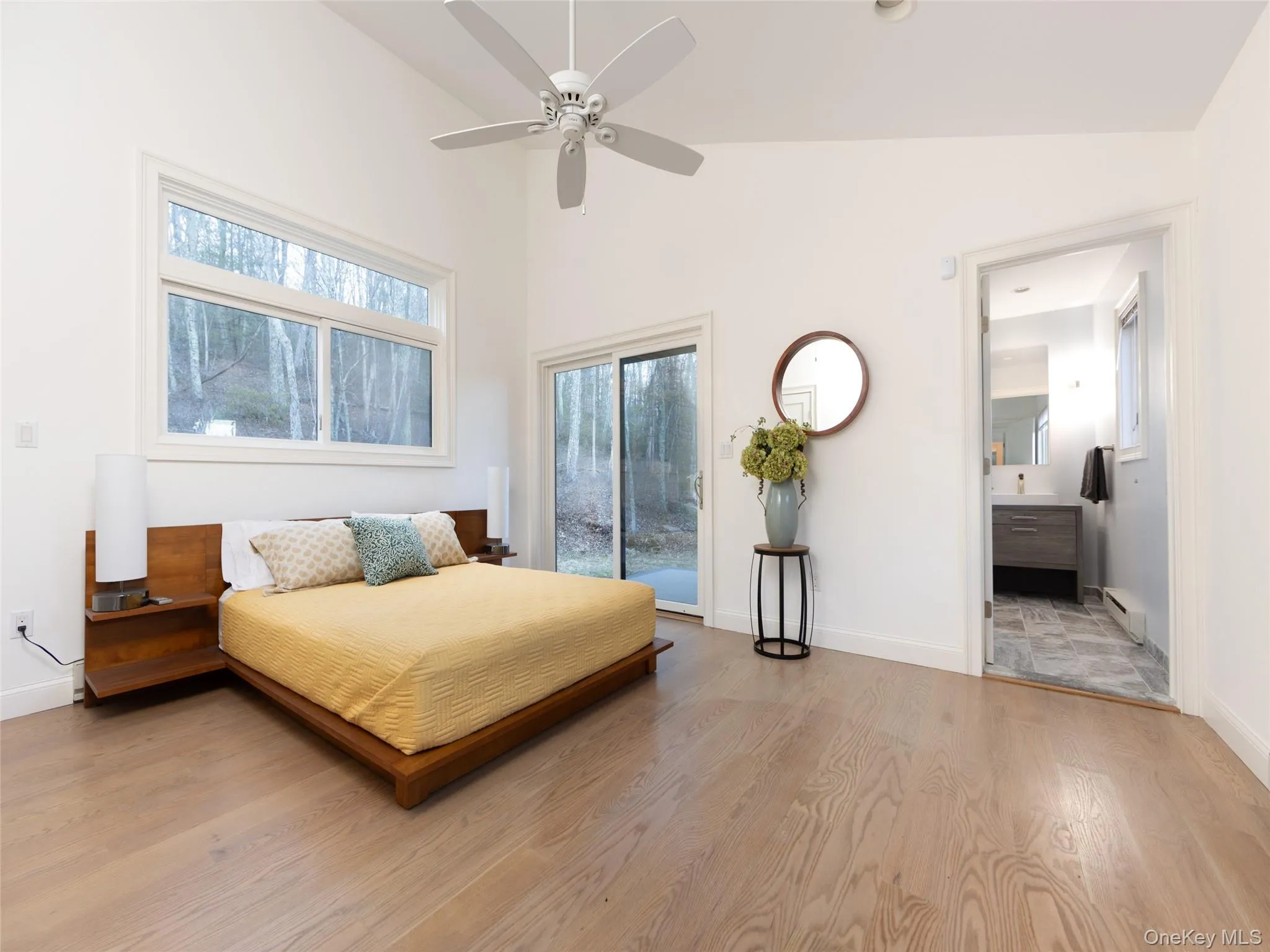 Bedroom featuring baseboards, baseboard heating, light wood finished floors, ensuite bath, and access to outside Bedroom featuring baseboards, baseboard heating, light wood finished floors, ensuite bath, and access to outside