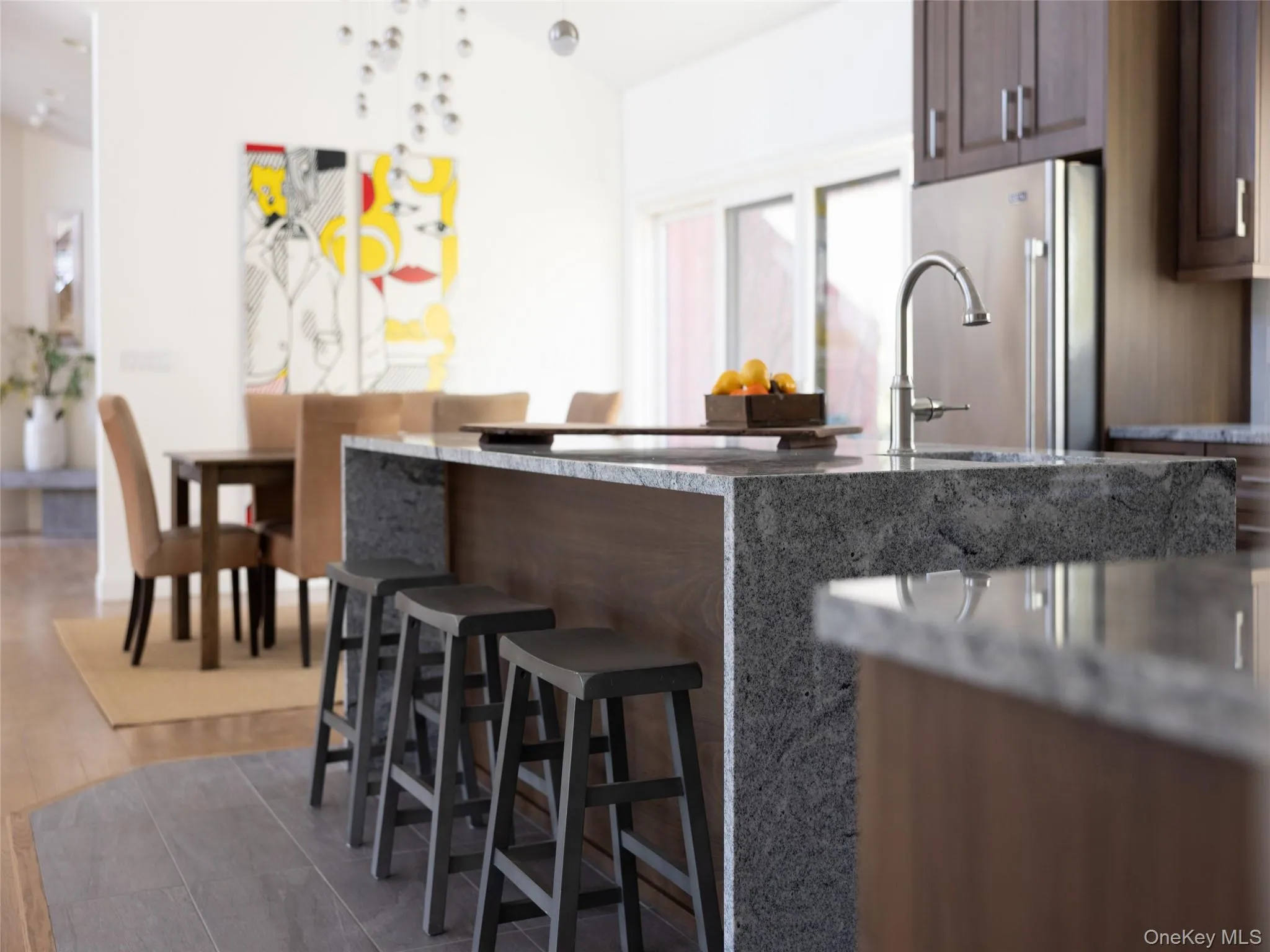 Kitchen with freestanding refrigerator, a kitchen breakfast bar, dark brown cabinetry, light stone countertops, and dark wood-type flooring Kitchen with freestanding refrigerator, a kitchen breakfast bar, dark brown cabinetry, light stone countertops, and dark wood-type flooring