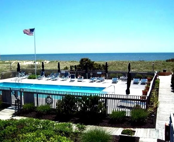 Pool featuring a water view, fence, and a patio Pool featuring a water view, fence, and a patio