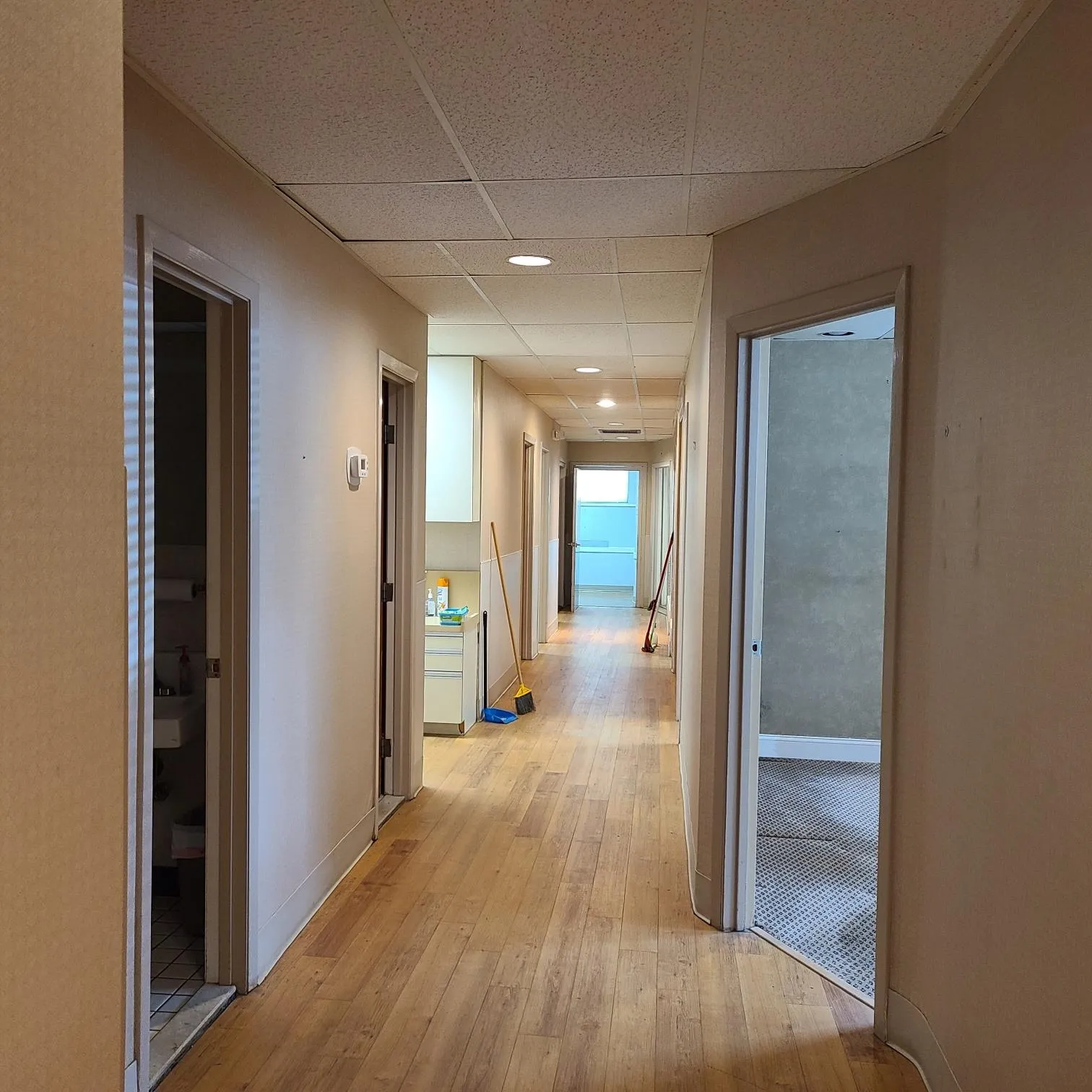 Hall featuring baseboards, light wood-style flooring, and a paneled ceiling Hall featuring baseboards, light wood-style flooring, and a paneled ceiling