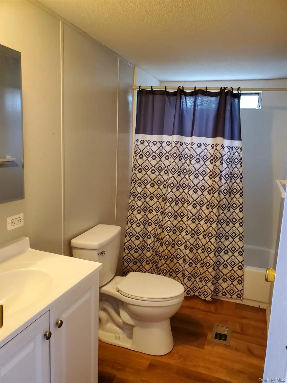 Bathroom with toilet, vanity, wood finished floors, a textured ceiling, and visible vents Bathroom with toilet, vanity, wood finished floors, a textured ceiling, and visible vents