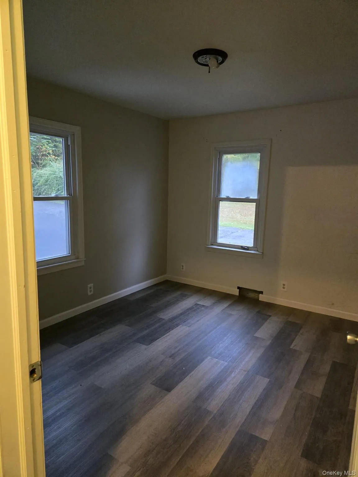 Unfurnished room with baseboards and dark wood-style flooring Unfurnished room with baseboards and dark wood-style flooring