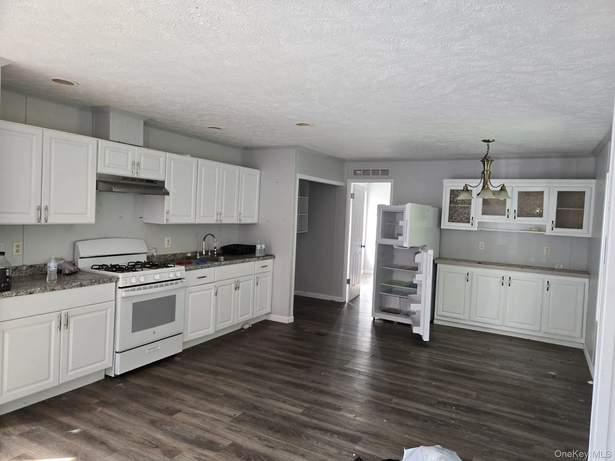 Kitchen featuring dark wood-type flooring, under cabinet range hood, a sink, white cabinets, and white range with gas stovetop Kitchen featuring dark wood-type flooring, under cabinet range hood, a sink, white cabinets, and white range with gas stovetop