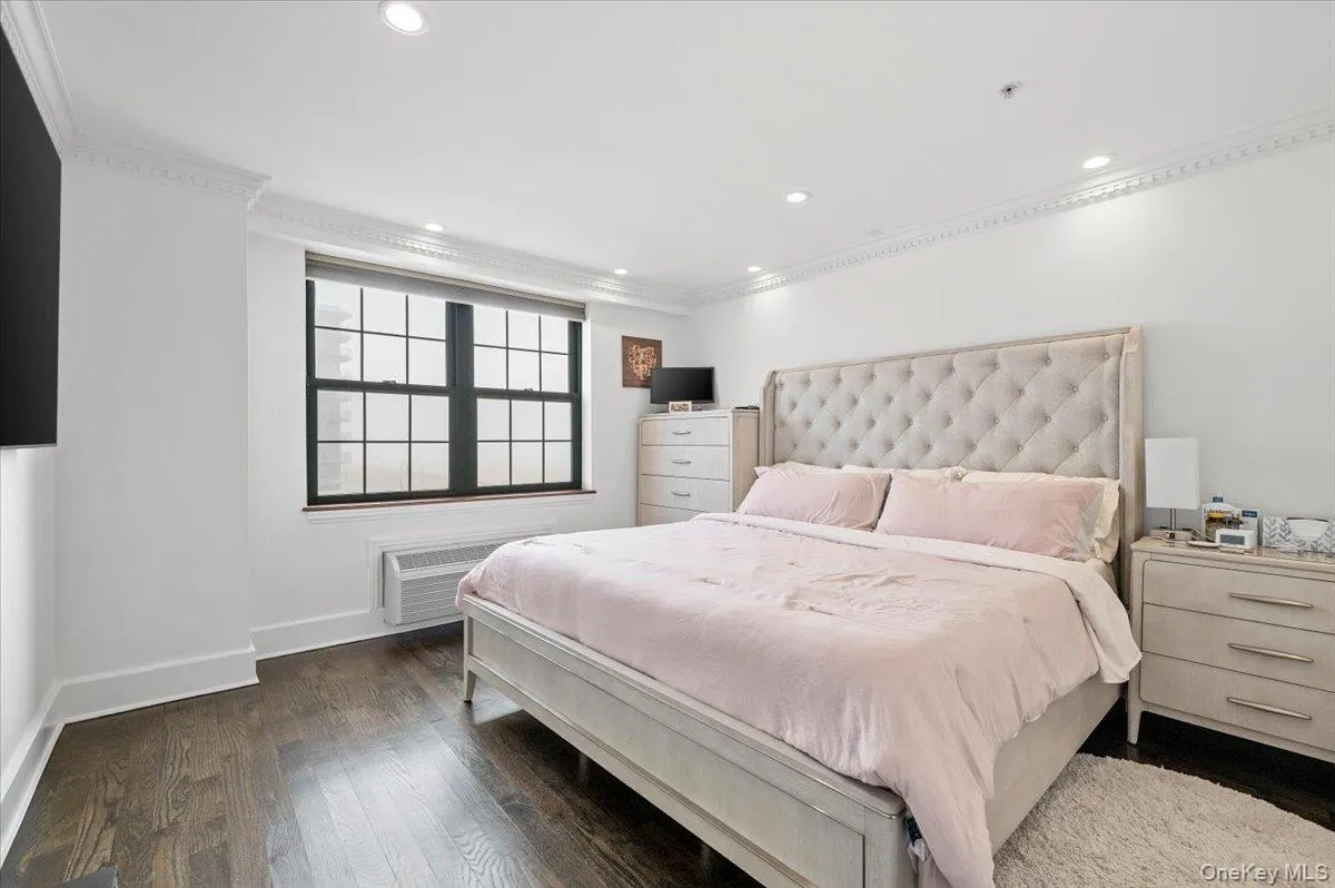 Bedroom with crown molding, recessed lighting, an AC wall unit, baseboards, and dark wood finished floors Bedroom with crown molding, recessed lighting, an AC wall unit, baseboards, and dark wood finished floors