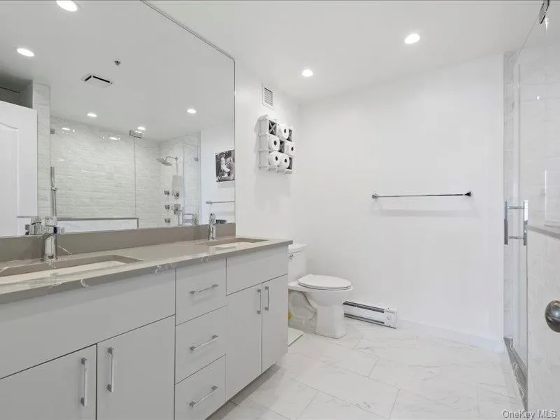 Full bath with marble finish floor, a sink, visible vents, and baseboard heating Full bath with marble finish floor, a sink, visible vents, and baseboard heating