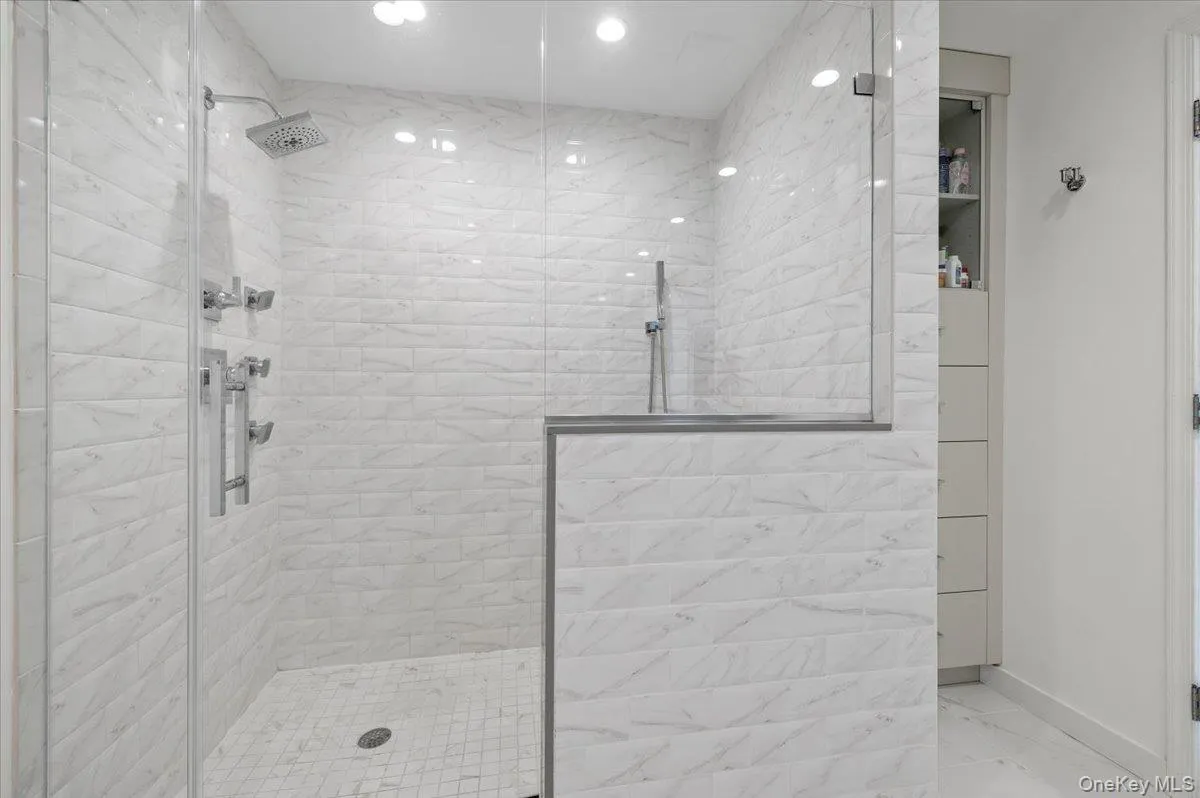 Bathroom with marble finish floor, a stall shower, and baseboards Bathroom with marble finish floor, a stall shower, and baseboards